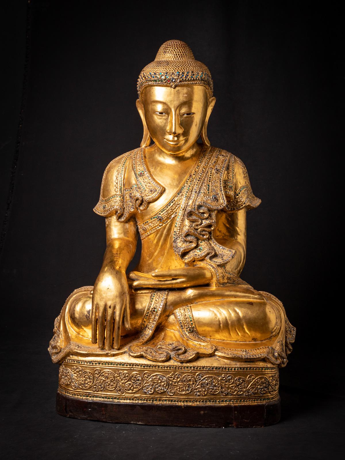 This large old Burmese Mandalay Buddha statue is a stunning mid-20th century masterpiece from Burma (Myanmar). Expertly carved from wood and gilded with 24-karat gold, the statue stands 90.5 cm high, 61.5 cm wide, and 41 cm deep, with a substantial
