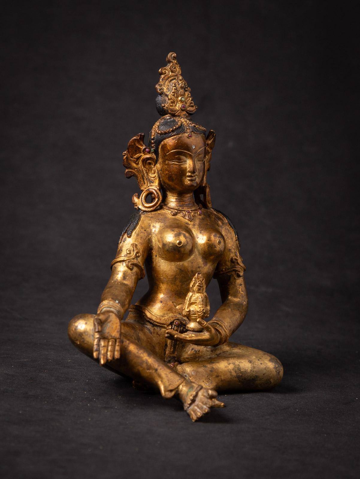This Old bronze Nepali Basundhara statue Inlaid with real gem stones is an exquisite representation of a revered figure in Tibetan Buddhism. Crafted from bronze, it stands at a height of 20,2 cm, with dimensions of 14,5 cm in width and 12 cm in