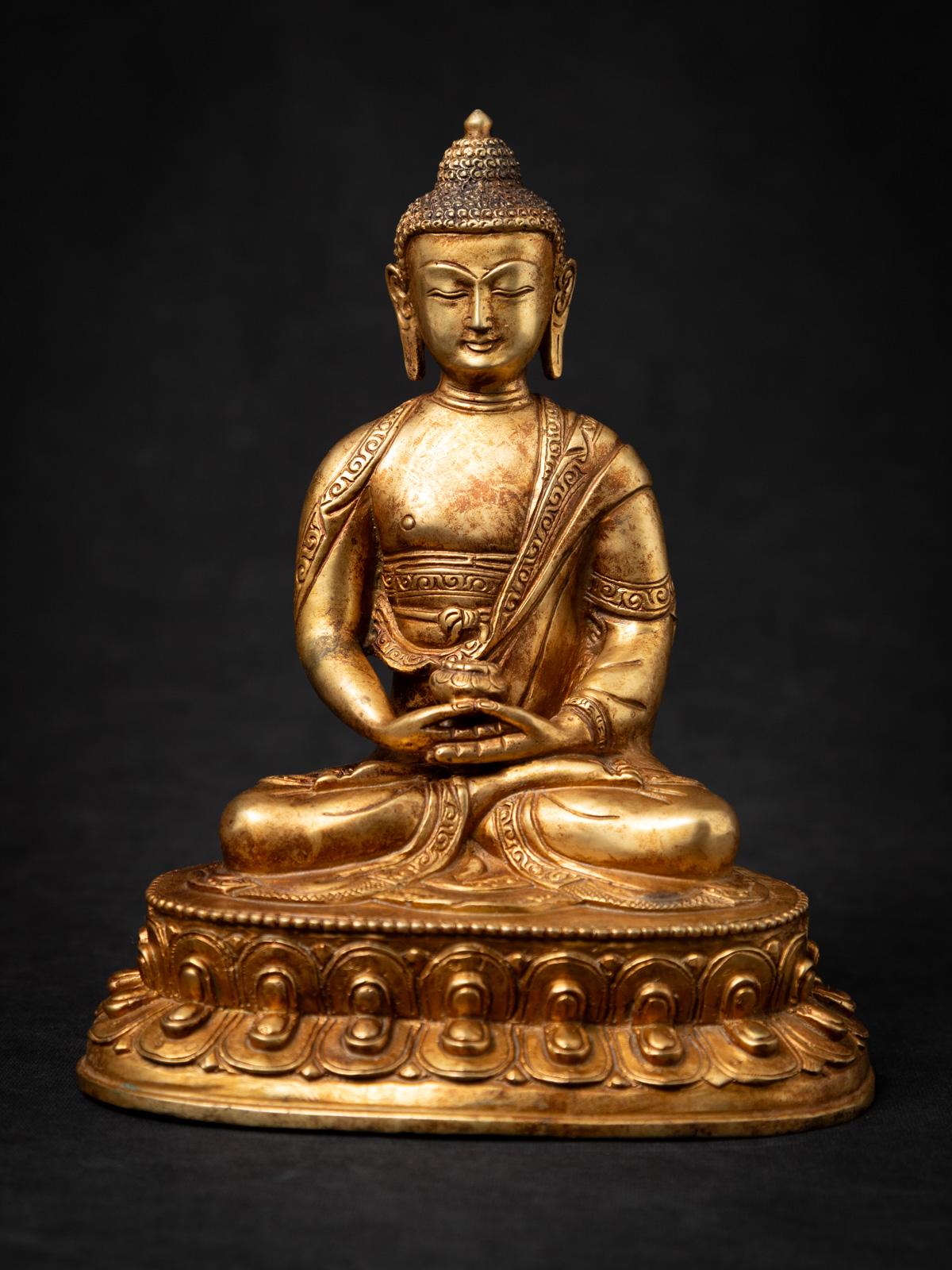 Esta elegante estatua de Buda nepalí de bronce antiguo es una cautivadora pieza de arte tradicional del Himalaya, elaborada en Nepal a mediados del siglo XX. Hecha de bronce macizo y dorada a fuego con oro de 24 quilates, la estatua irradia un