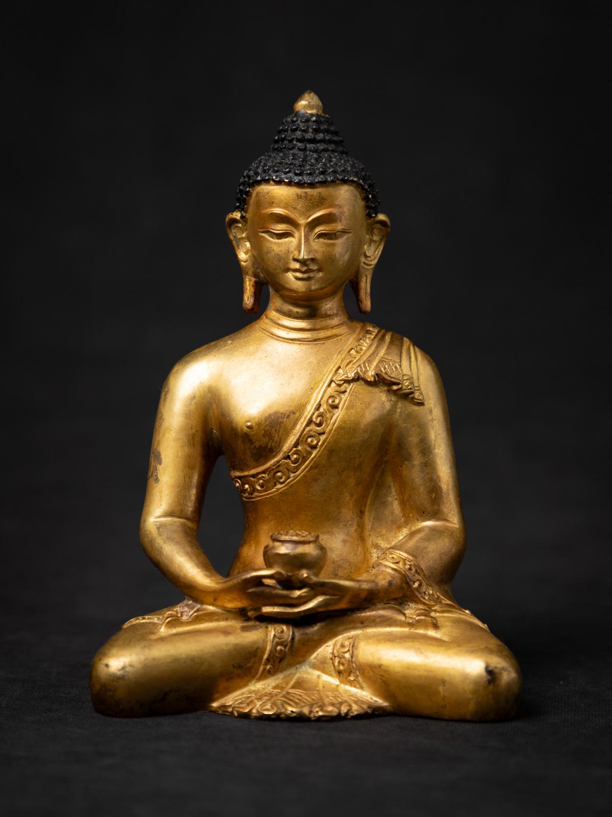 Diese schöne alte nepalesische Buddha-Statue aus Bronze ist ein fein gearbeitetes Stück spiritueller Kunst, das aus Nepal stammt und auf die Mitte des 20. Jahrhunderts datiert wird. Die aus hochwertiger Bronze gefertigte und mit 24-karätigem Gold