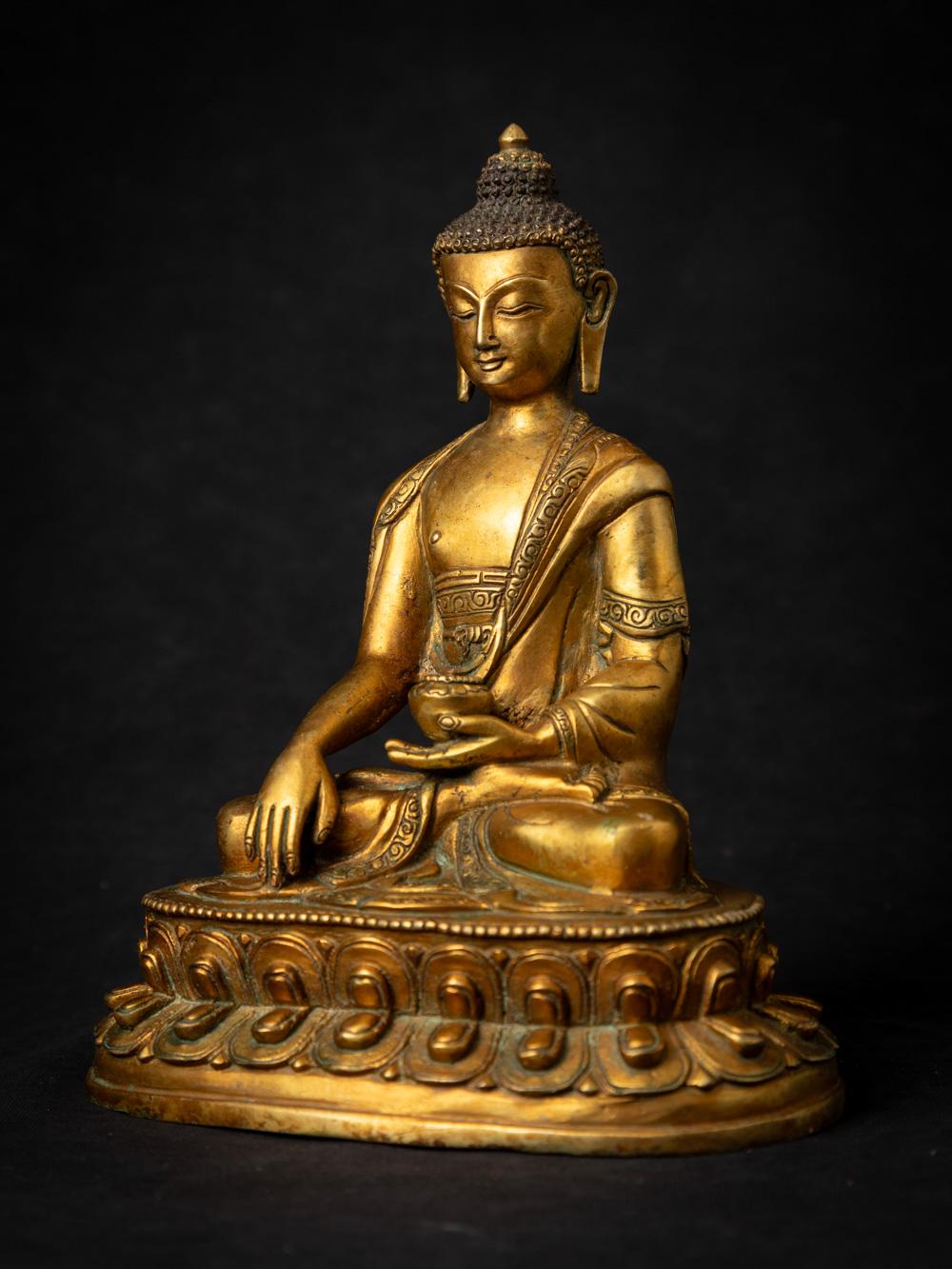 This old bronze Nepali Buddha statue is a captivating and spiritually significant piece of art. Crafted from bronze, it stands at a height of 21.3 cm with dimensions of 17.2 cm in width and 12.4 cm in depth. The statue beautifully depicts the Buddha