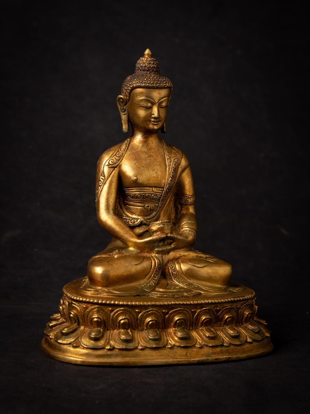 This old bronze Nepali Buddha statue is a captivating and spiritually significant piece of art. Crafted from bronze, it stands at a height of 21.2 cm with dimensions of 17.3 cm in width and 12.4 cm in depth. The statue beautifully depicts the Buddha