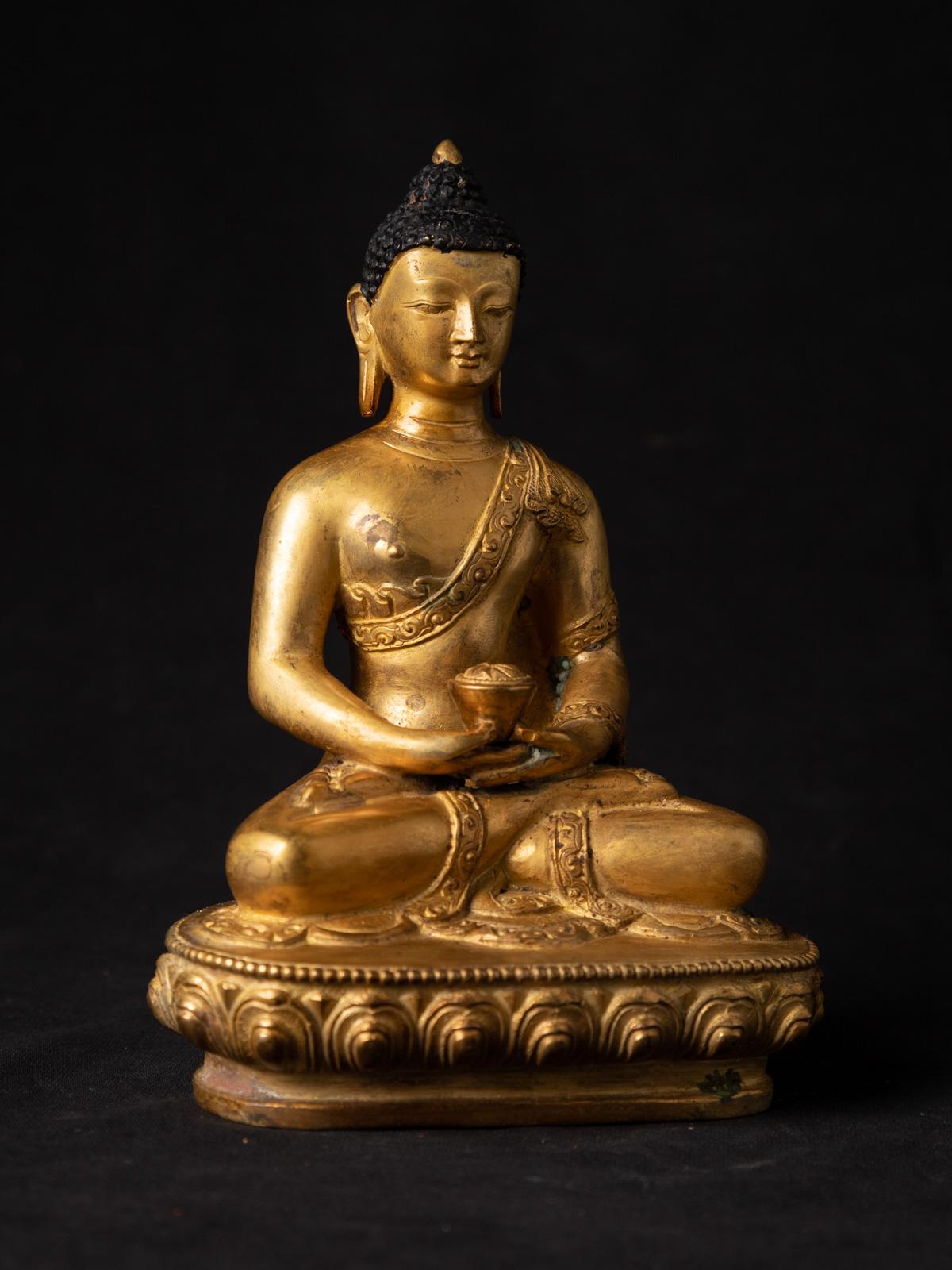 This old bronze Nepali Buddha statue is a captivating and spiritually significant piece of art. Crafted from bronze, it stands at a height of 18.3 cm with dimensions of 12.7 cm in width and 8.8 cm in depth. The statue beautifully depicts the Buddha