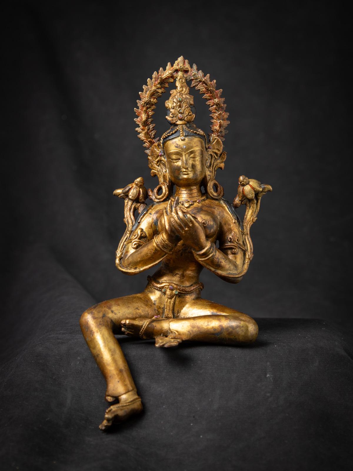 Cette statue de Tara verte népalaise en bronze ancien est un chef-d'œuvre captivant du milieu du XXe siècle qui célèbre l'art sacré du Népal. Réalisée en bronze massif et dorée à l'or fin 24 carats, elle est ornée de véritables pierres précieuses