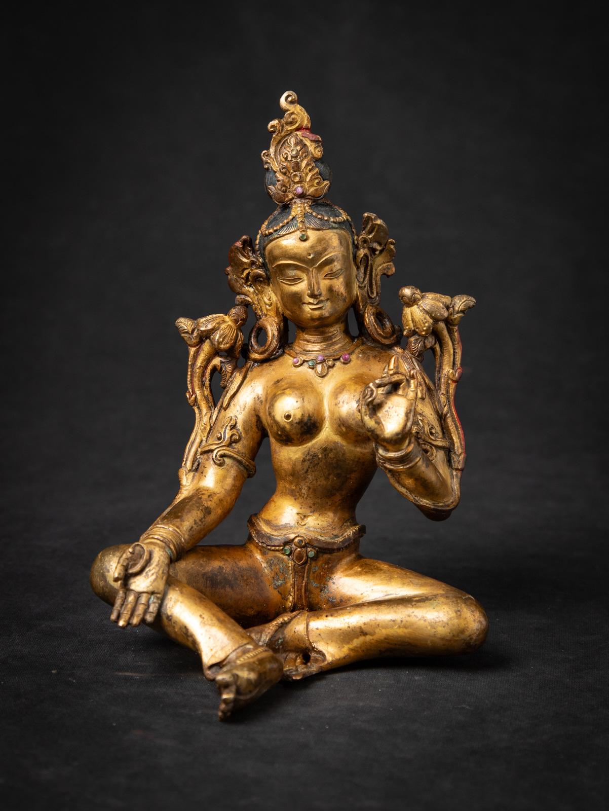 Esta antigua estatua nepalí de bronce de Tara Verde es una grácil encarnación de la compasión y la protección, hecha a mano en Nepal a mediados del siglo XX. Hecha de bronce y dorada al fuego con oro de 24 quilates, la estatua mide 20,2 cm de alto,