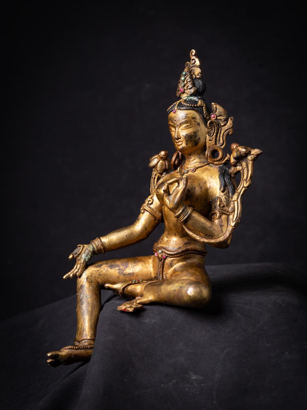 This old bronze Nepali Green Tara statue is an exquisite representation of a revered figure in Tibetan Buddhism. Crafted from bronze, it stands at a height of 26 cm, with dimensions of 14 cm in width and 11.8 cm in depth, making it a beautifully