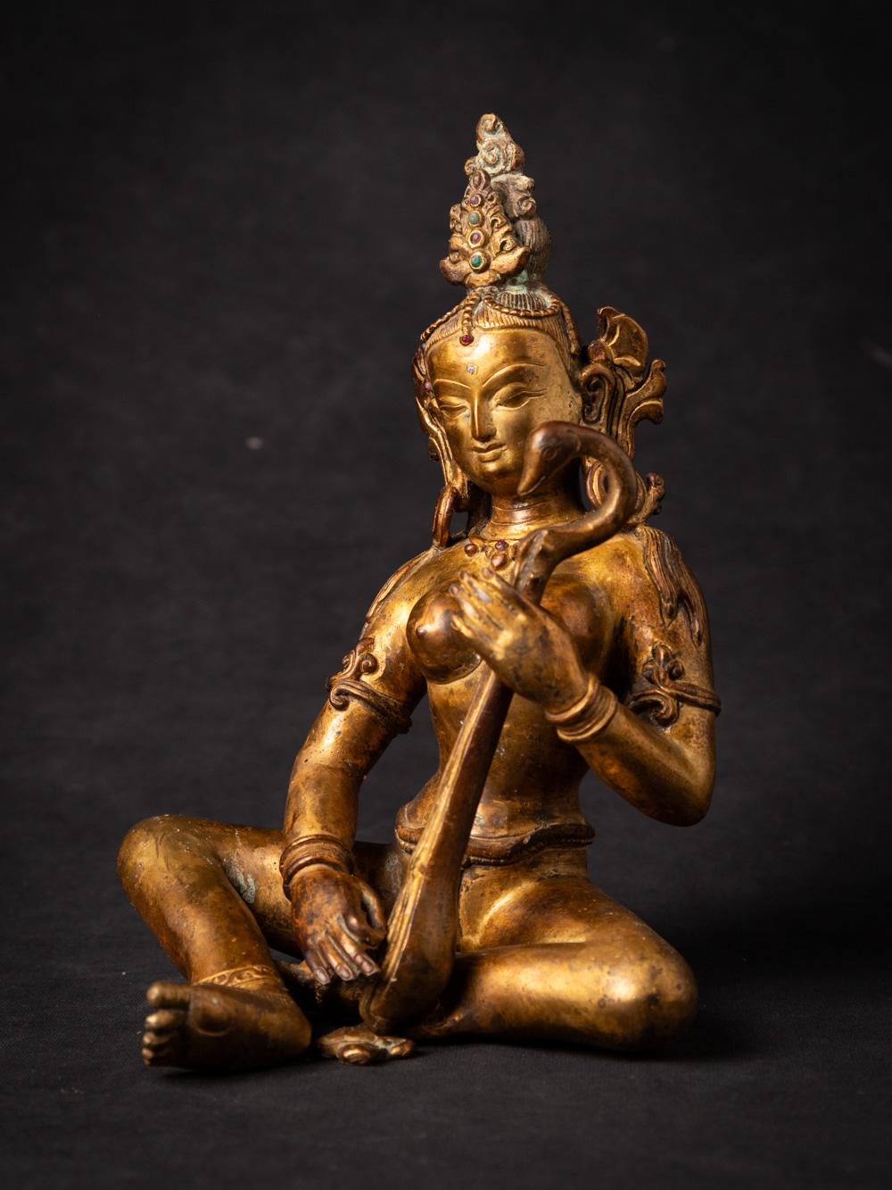 The old bronze Nepali Saraswati statue is a captivating and spiritually significant artifact originating from Nepal. Crafted from bronze and adorned with fire gilding in 24-karat gold, this statue stands at 20.2 cm in height and measures 14.5 cm in