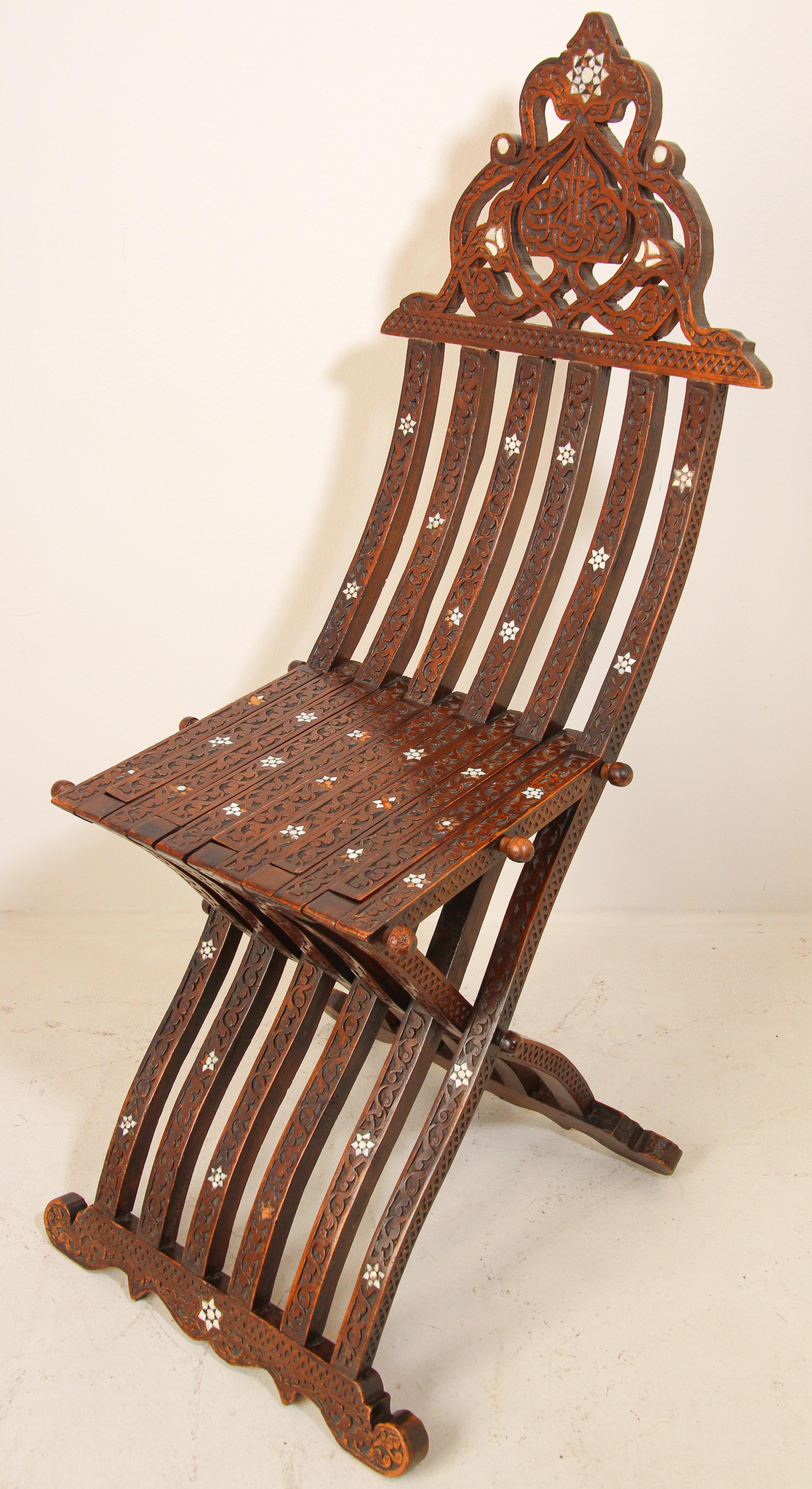 Antique Middle Eastern Egyptian Moorish walnut wood folding chair with intricate foliate carving and mother of pearl, shell inlays.
Arabian Syrian style folding chair inlaid with mother of pearl stars designs, hand carved with Arabic calligraphy