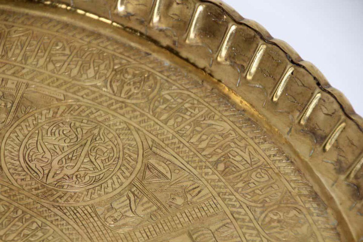 Middle Eastern Egyptian antique round brass tray. The handcrafted circular brass platter is decorated and hammered with Islamic Moorish designs. Heavy brass with very fine hand chased floral and geometric Arabic designs. The ray is telling a story