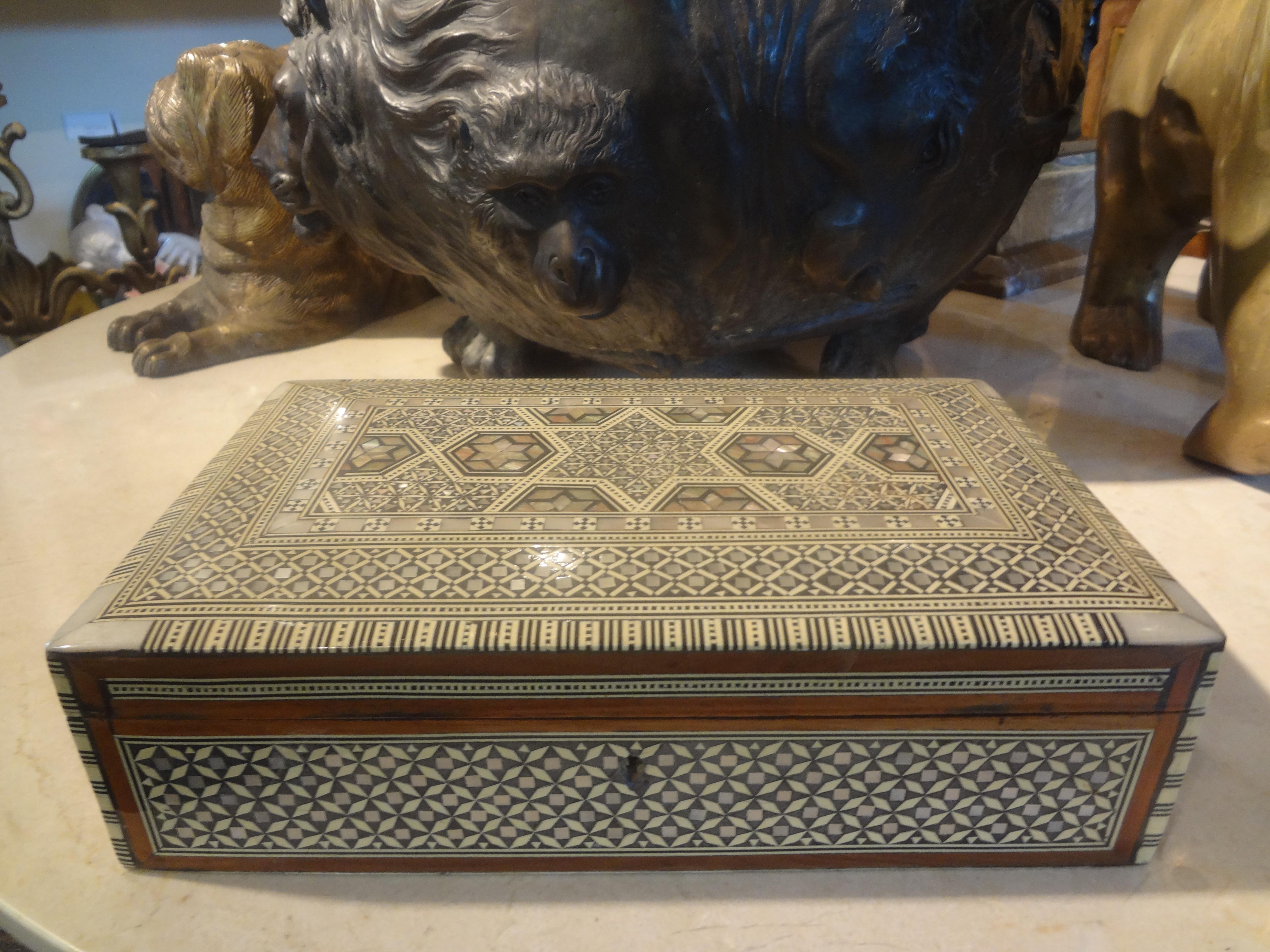 Middle Eastern/Moorish Decorative Box Of Inlaid Woods And Mother-Of-Pearl.
Lovely Arabesque style decorative box or coffee table box with a geometric mosaic pattern of mixed woods and mother-of-pearl. This stunning box has a felt lined interior and