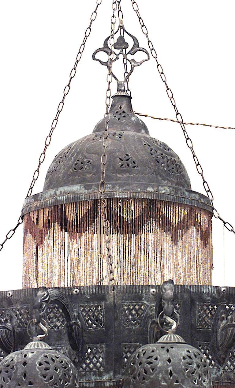Middle Eastern Moorish-style (20th Century) patinated brass filigree 2 tiered chandelier with 18 bird head arms holding dome shades. Gold glass beaded fringe.
