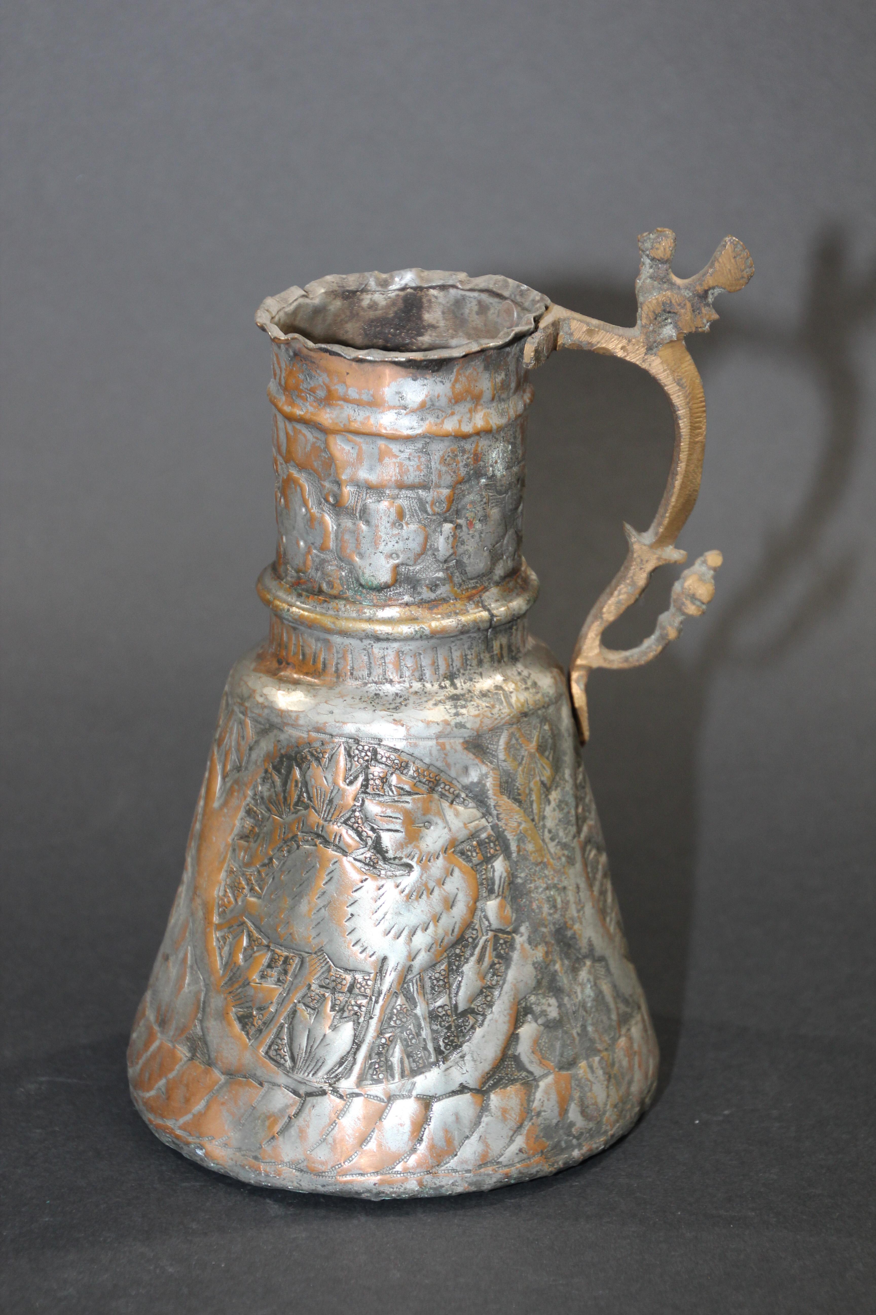 19th century Middle Eastern Arabian tinned copper coffee pot.
A bird on top of the handle.
Embossed, hand-hammered and chased tinned copper with figures and wild animal designs riveted finish on handle.
Missing lid, probably used to make coffee,