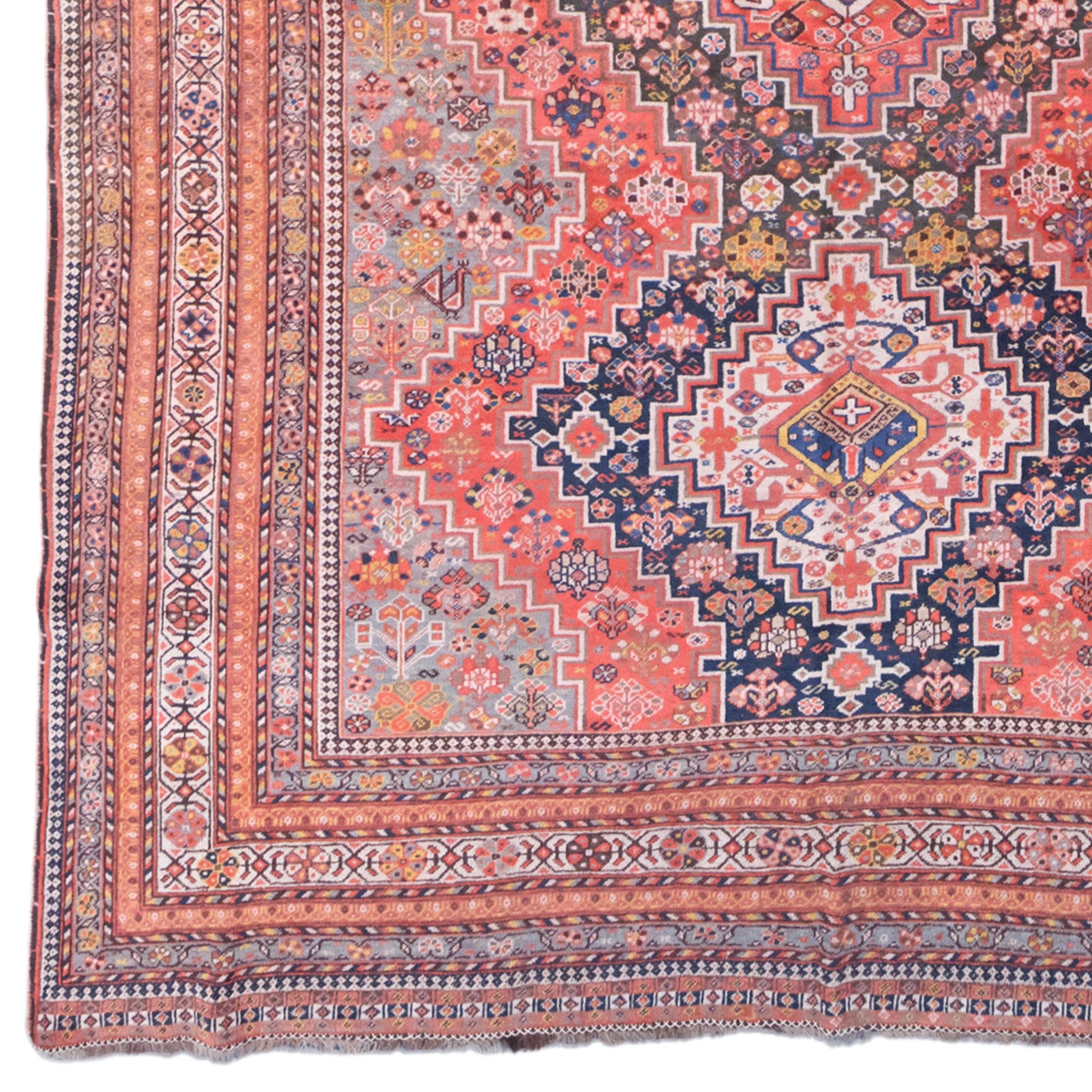 This unique antique Khamseh carpet is a masterpiece from the mid-19th century. Decorated with complex geometric patterns and motifs in red, blue and beige tones, this carpet attracts attention with its elegance and mastery. The diamond-shaped