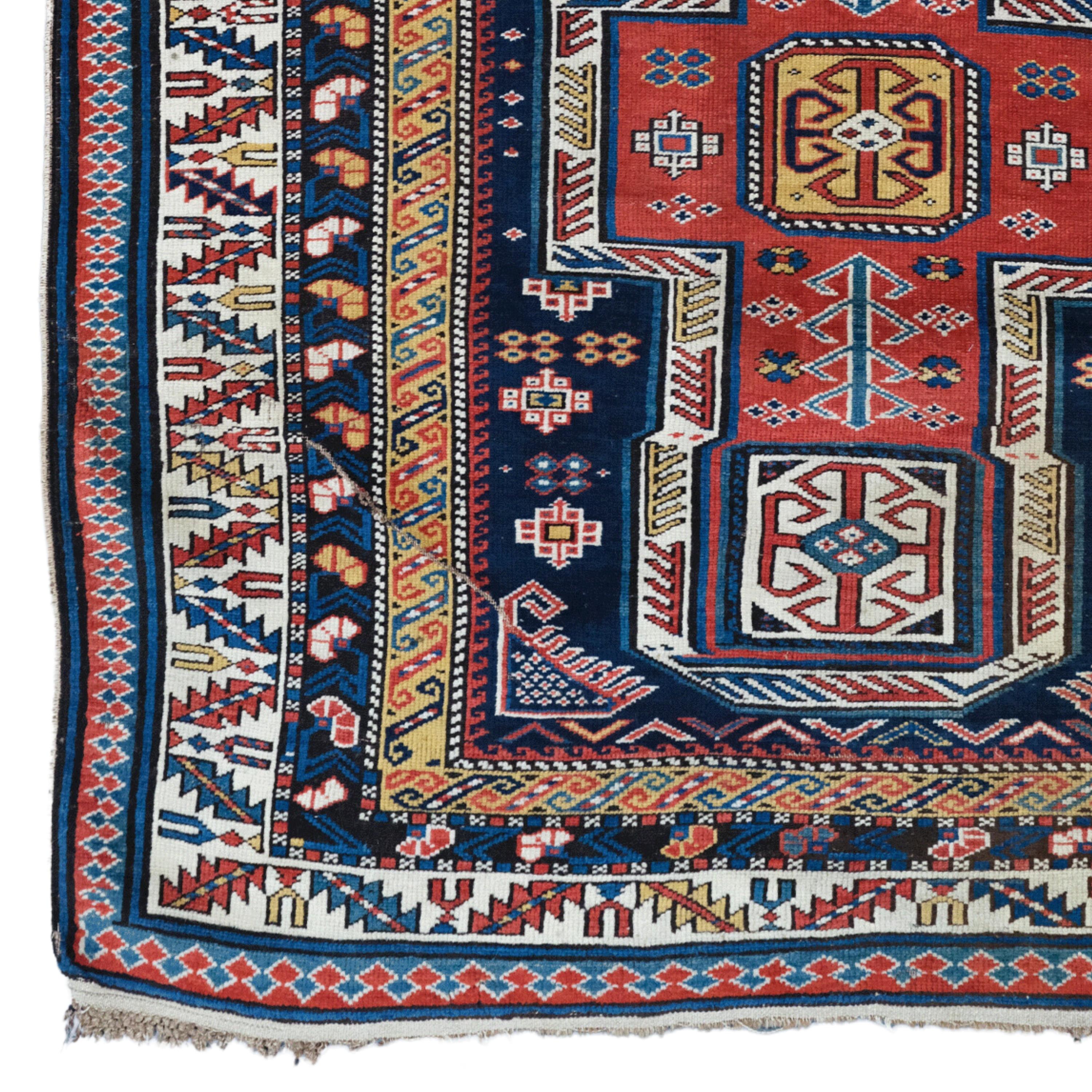 Portant la texture du temps, ce tapis ancien caucasien Shirvan du milieu du 19e siècle est un exemple unique de l'artisanat traditionnel. Les tons bleus et rouges profonds sont mélangés à des motifs géométriques complexes et décorés de détails