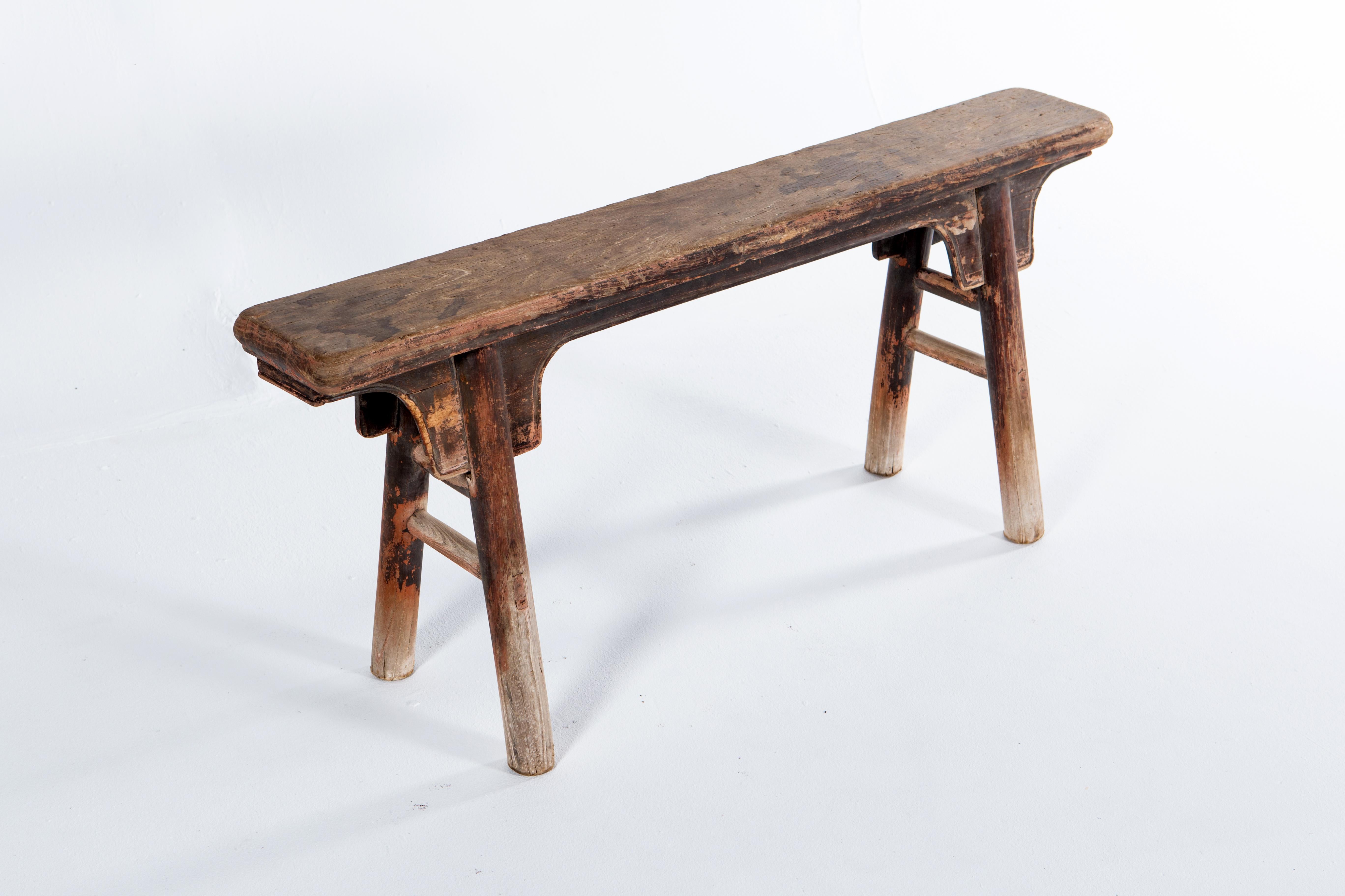 This classic two-person Chinese bench features simple cloud-motif stretchers, splayed legs, and traces of original lacquer. The antique patina is beautifully aged and original. Wear consistent with age and use.