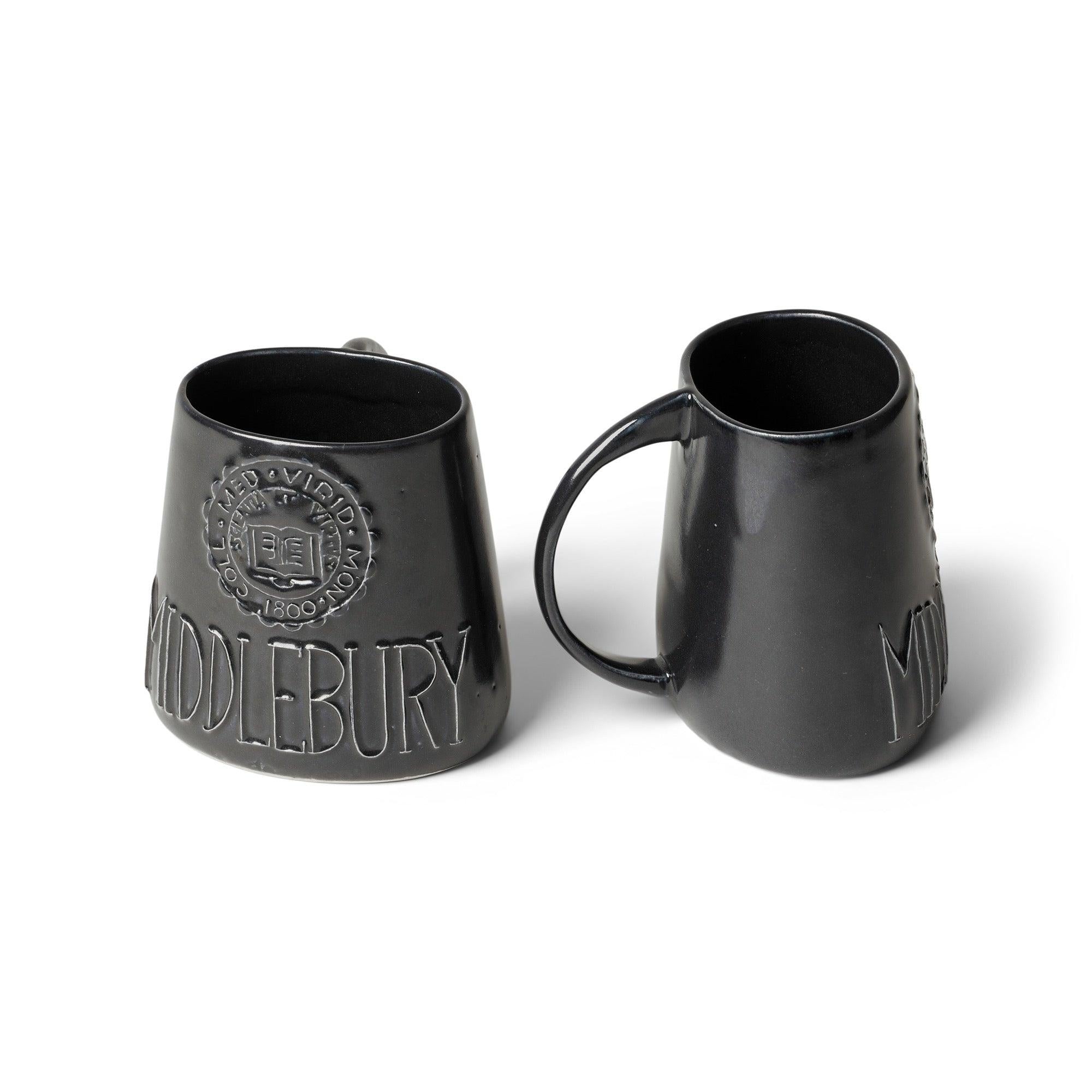 Keramikbecher mit ovaler Form und Henkel, verziert mit dem Emblem des Middlebury College. Mit einer schwarzen Glasur versehen.