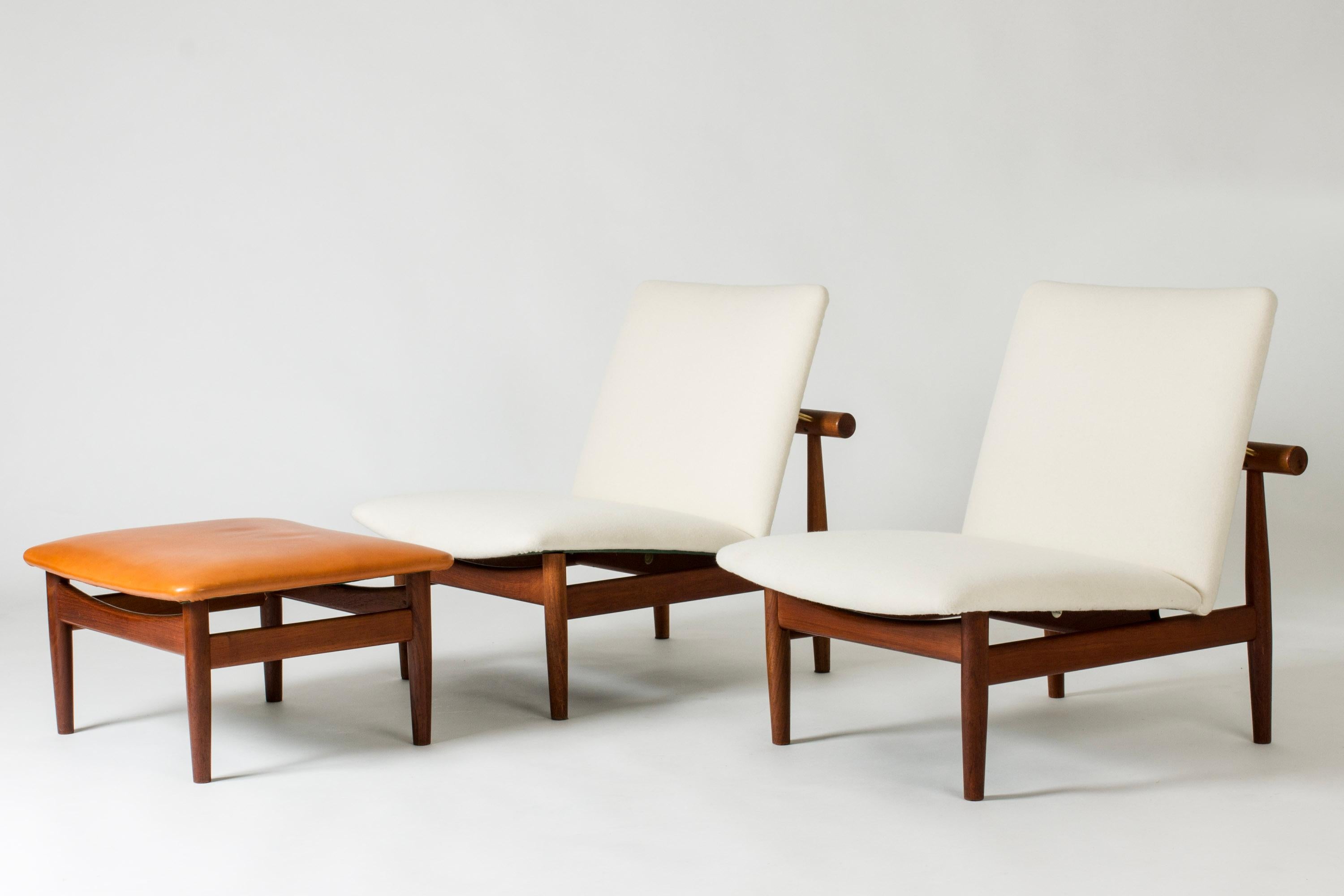 Pair of elegant “Japan” lounge chairs, made from teak with clean lines. White wool upholstery. Shared ottoman with cognac colored leather.
