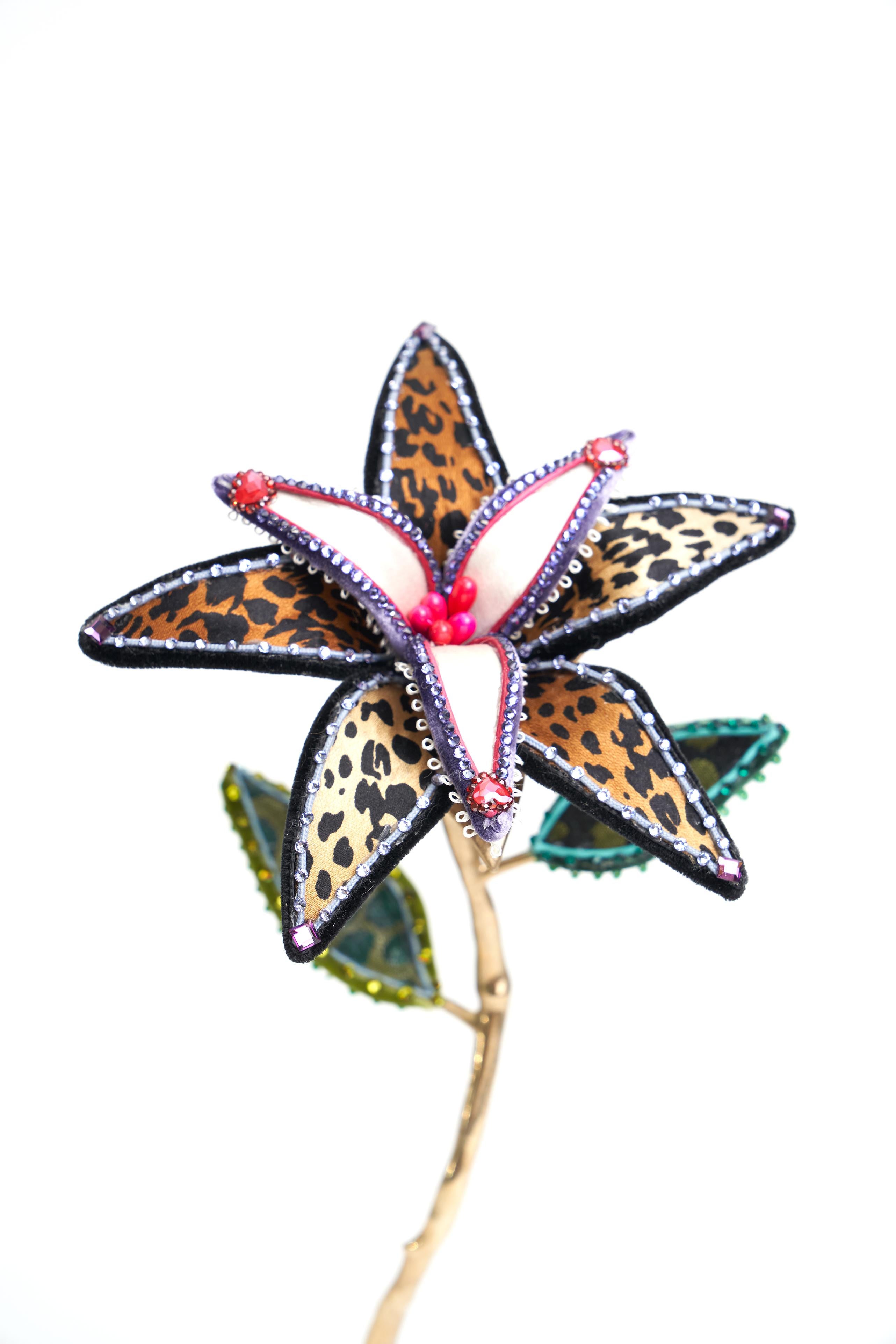 Schwarze und lilafarbene Leopardenblume aus Seide und Samt, die auf einem speziell entworfenen, pfotenförmigen Messingfuß ruht. Geschmückt mit Vintage-Verzierungen, europäischen Kristallen und Vintage-Kunstblüten. Entworfen und handgefertigt in NYC. 