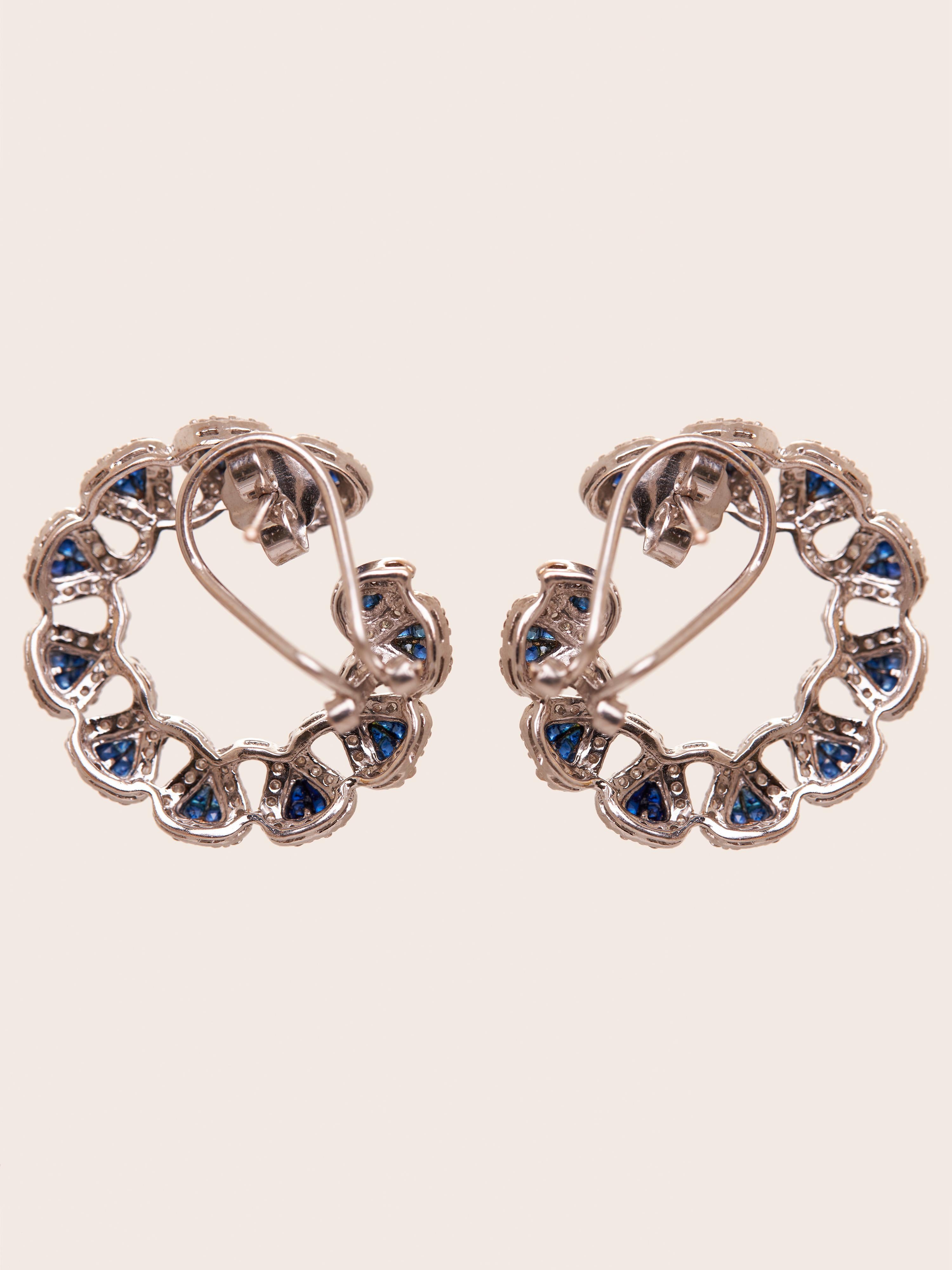 The Midnight Halo Sapphire earrings from our Invisible setting colour stone collection are an enchanting blend of dazzling blue sapphires and sparkling diamonds. Crafted in 14KT gold, the earrings boast an intricate loop design, creating a stunning