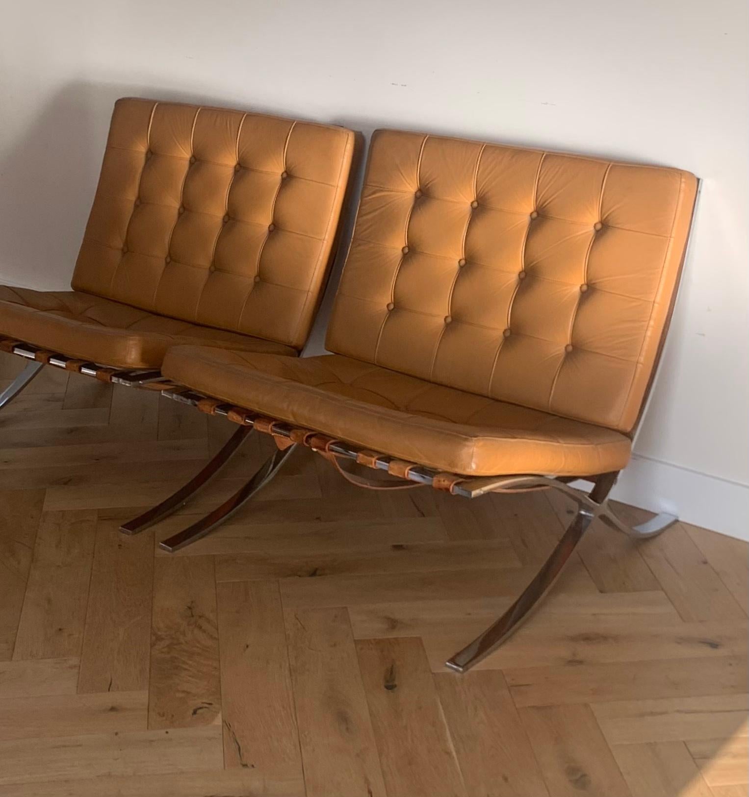 A pair of Mies van der Rohe Barcelona chairs in cognac. These are 1960s reproduction of the 1929 original design, discerned by the steel frame, real leather belting, and the vintage screws. An iconic Bauhaus triumph which recalls the ancient folding