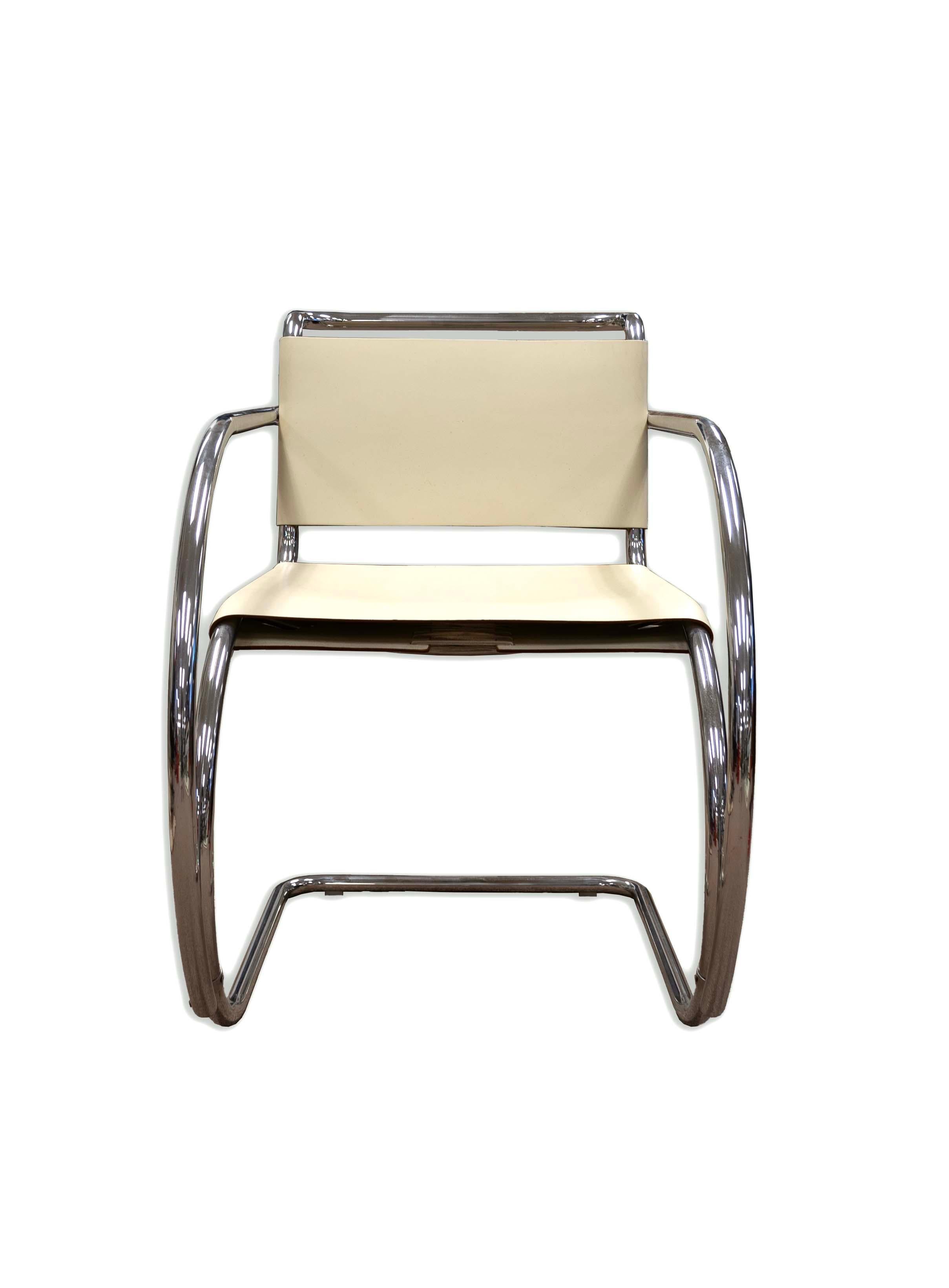 Sleek and timeless, this Mies van der Rohe Tubular Chrome Arm Chair is a masterpiece of Mid-Century Modern design. The chair's graceful curves and reflective chrome frame create an airy feel, while the creamy leather-look upholstery adds a touch of