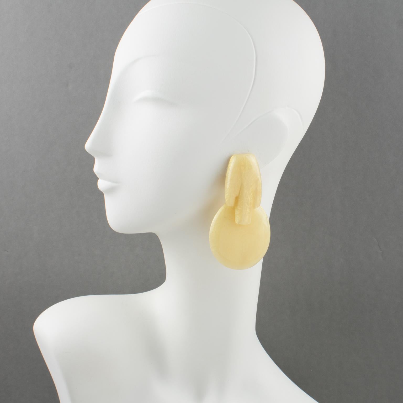 These rare, artisan-studio, handcrafted modernist resin clip-on earrings were created by Marie-Thérèse and Christian Migeon, known as Migeon & Migeon. The stunning, oversized, dangling drop shape with a futuristic design features a light,