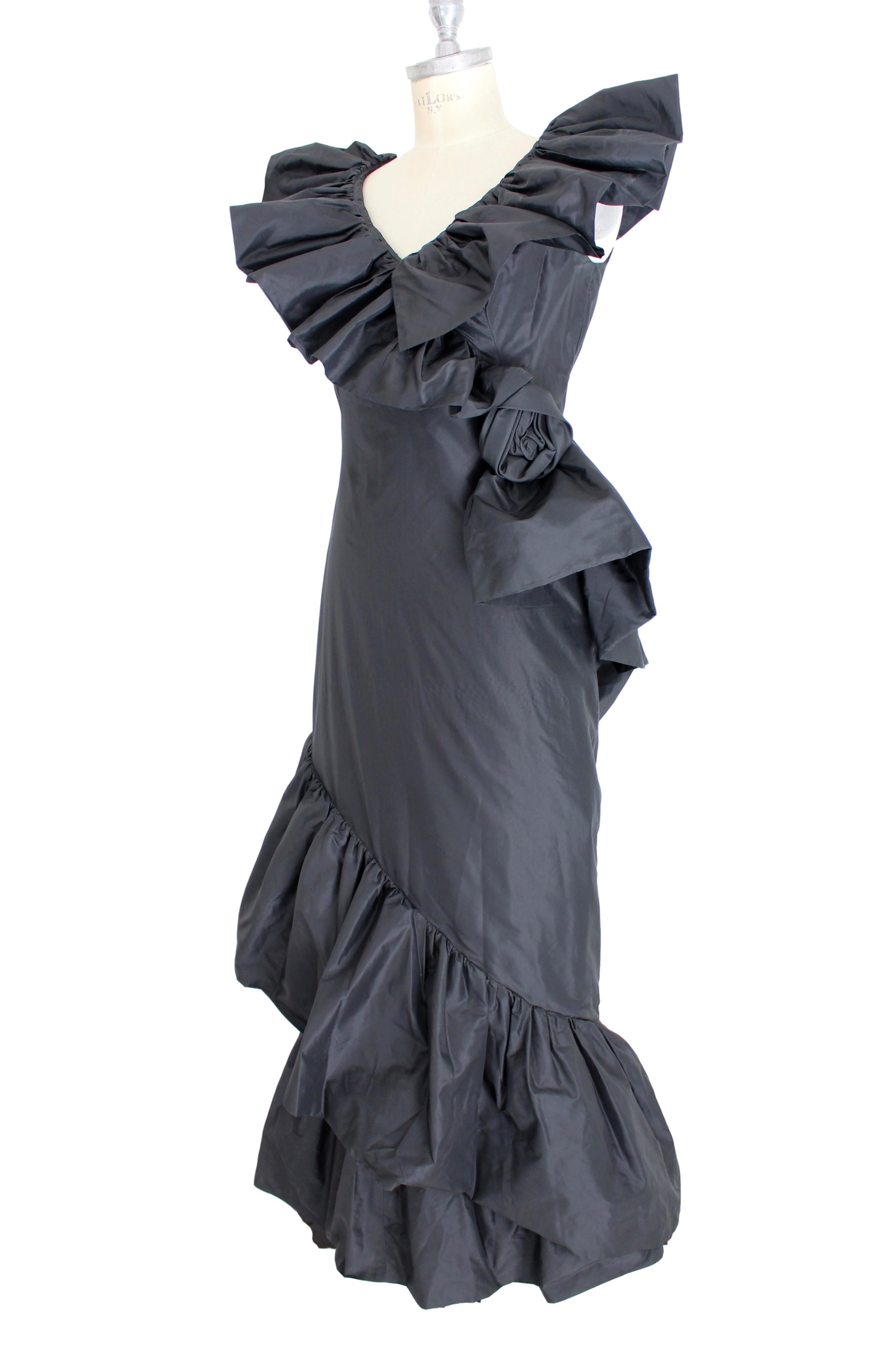 Mignon von Dorothy Farbo Vintage 80er Jahre Frau Kleid. Abendkleid, aus Seidentaft. Langes Modell mit Rüschen an den Schultern und asymmetrischer Länge, Blume an der Seite. Schwarze Farbe. Hergestellt in den USA. Ausgezeichneter