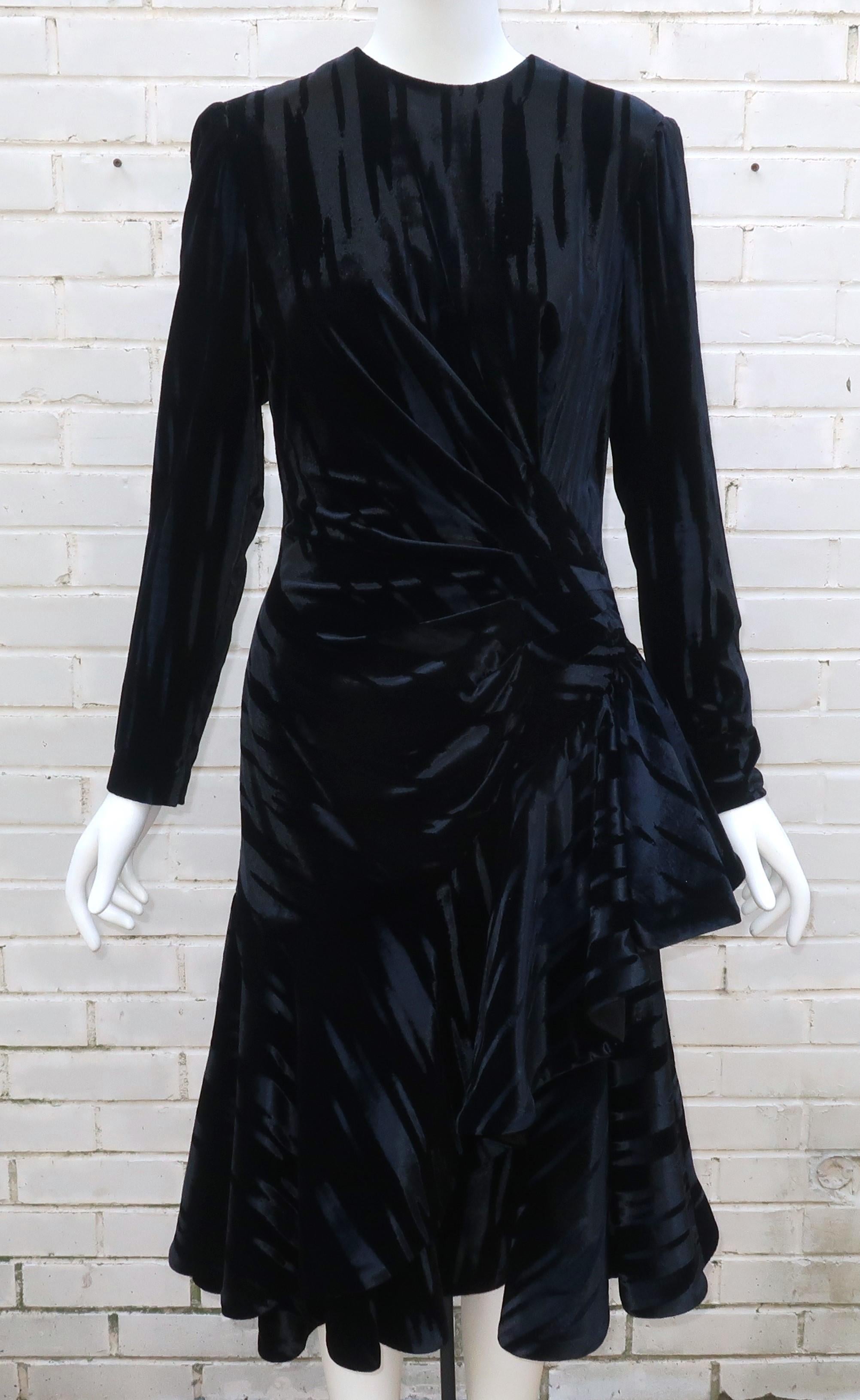 Un vestido de cóctel negro clásico con un toque extra de Anne Marie Gabalis para Mignon.  Este impresionante vestido combina una silueta ochentera, con hombros marcados y un volante asimétrico fruncido en la cadera, con un espectacular tejido de