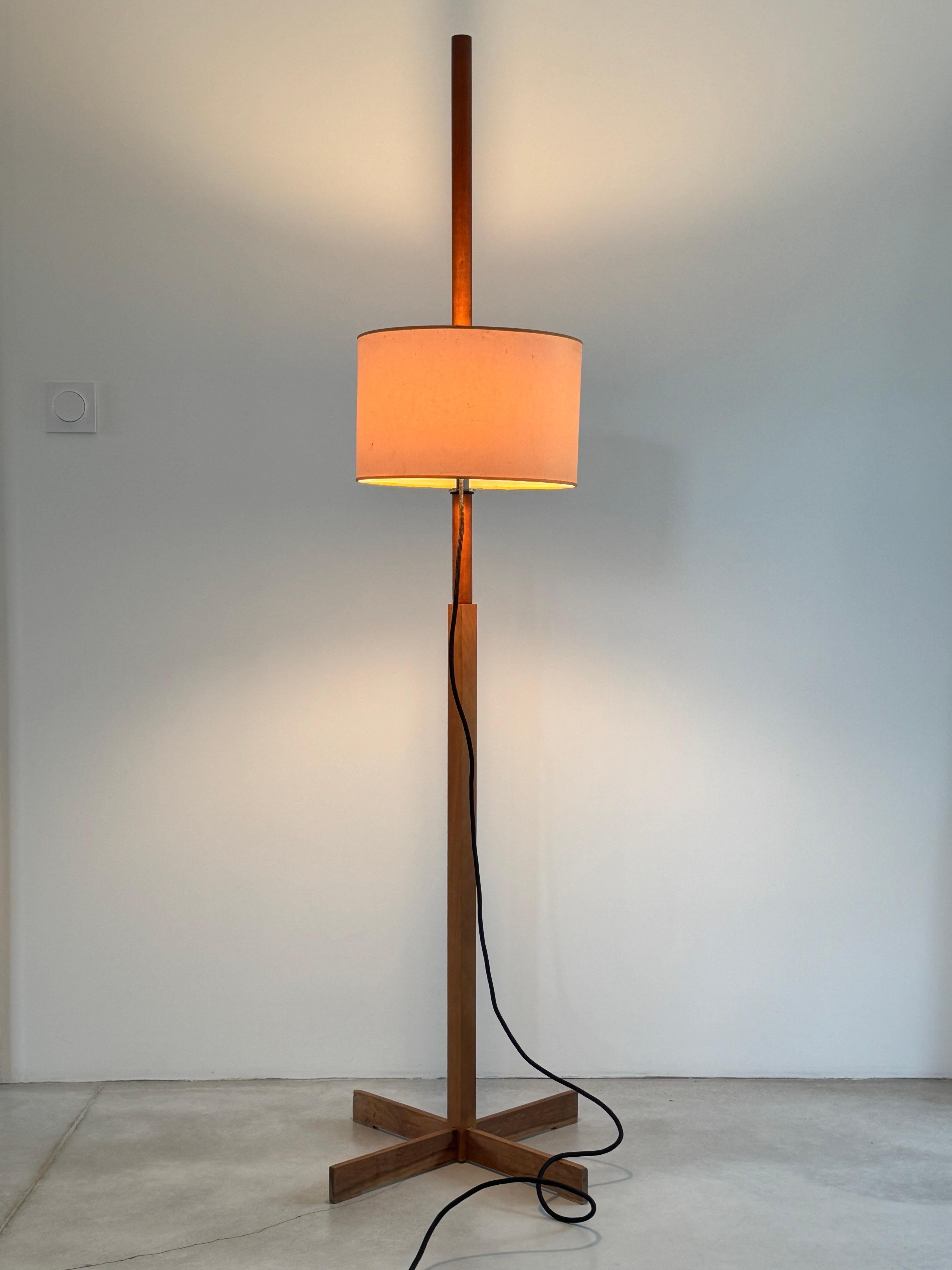 Original TMM floor lamp.

Design by Miguel MILA for Santa & Cole.


A cross-shaped base supports a square wooden shaft that becomes a circle in the middle. The shade can be moved up or down it, held at the required height by a simple rubber