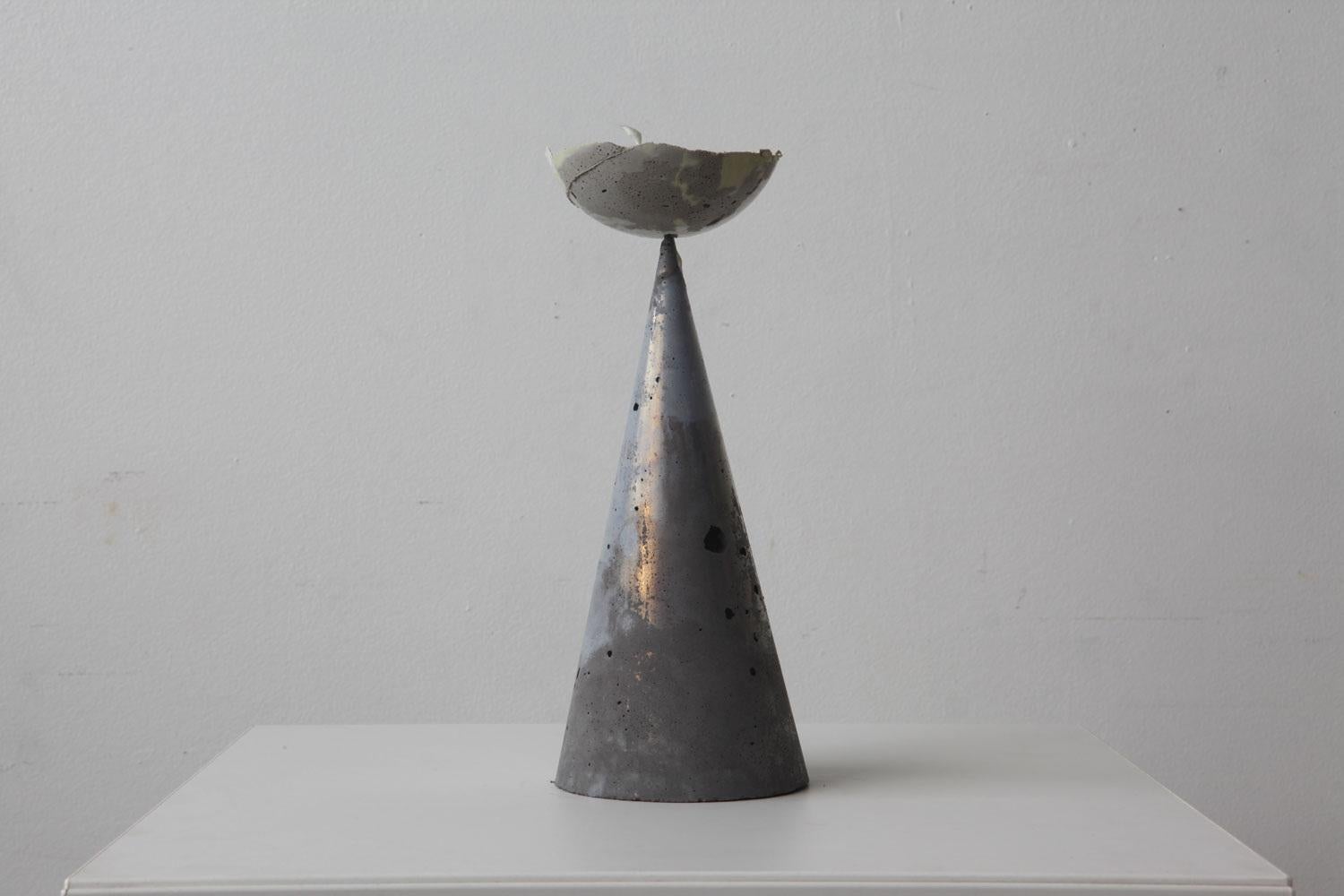 Moon Flower (2019) is a small contemporary abstract sculpture, featuring a concrete cone, with weathered details to create a rugged effect. Expertly balanced on the tip of the rectangular prism is a half-moon prism, thus giving it the name Moon