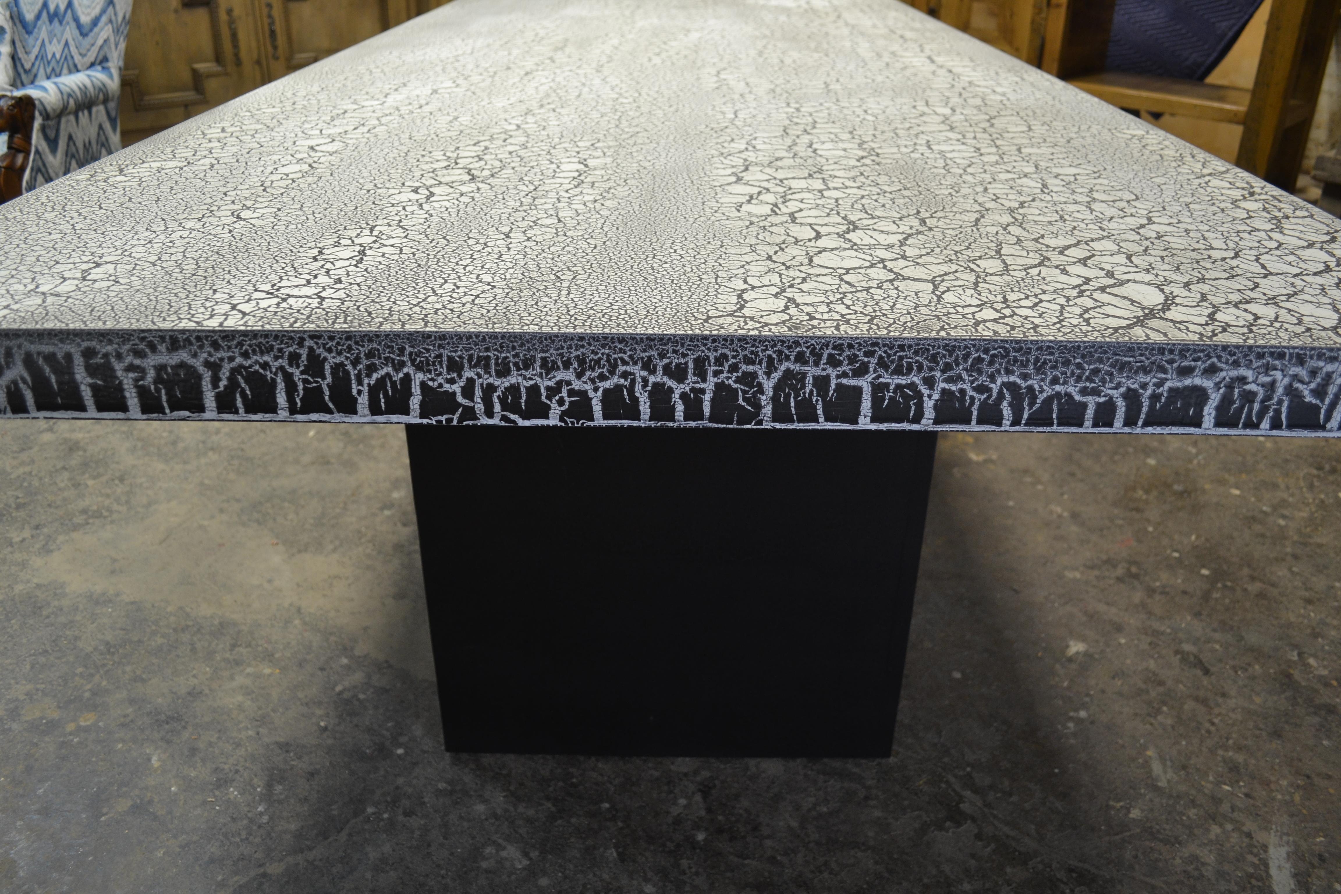 The Krackle table features a top crackle surface of white over black, an edge surface of black over white and a base in black on black crackle. The reveals of the legs and stretcher offer a sophisticated touch and the piece is available in any size