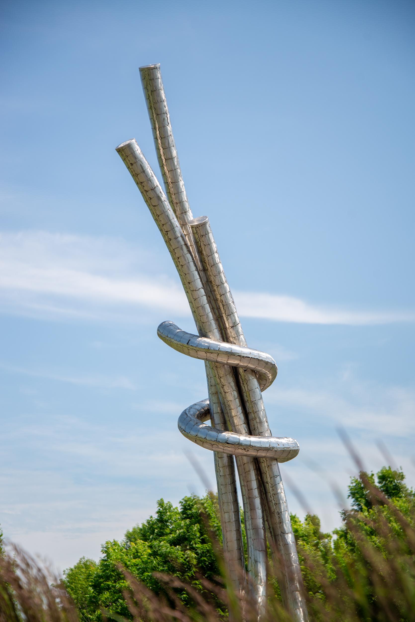 This monumental, contemporary, abstract, stainless steel sculpture was created by American sculptor Mike Hansel. Hansel has collaborated on public installations of outdoor sculptures throughout the United States. His distinctive metalwork is admired