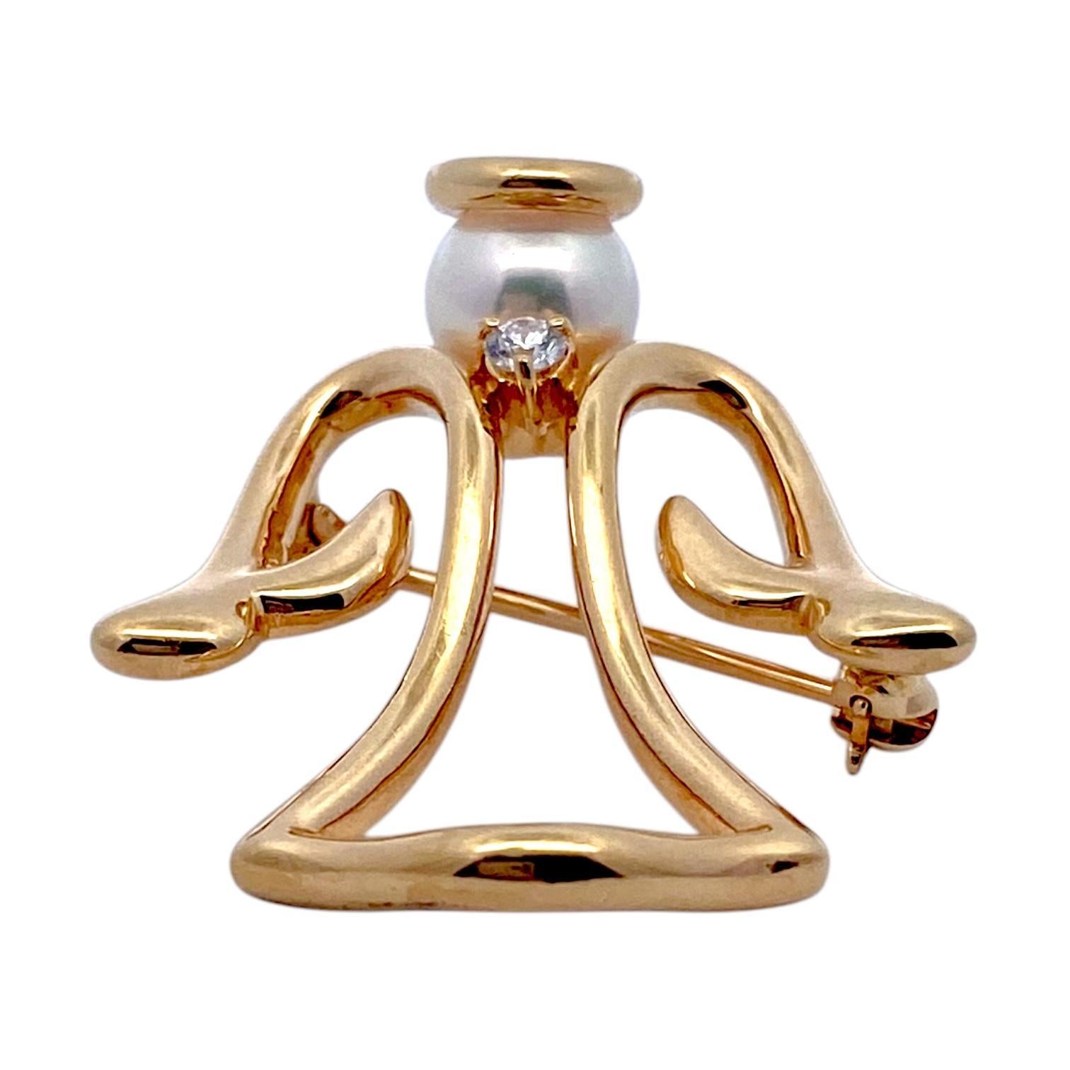 Crafted in 18K yellow gold, the brooch features a stylized angel design with flowing lines. The head is represented by a round cultured Akoya pearl in white, topped with a gold halo. A brilliant-cut diamond is set at the center, adding a touch of