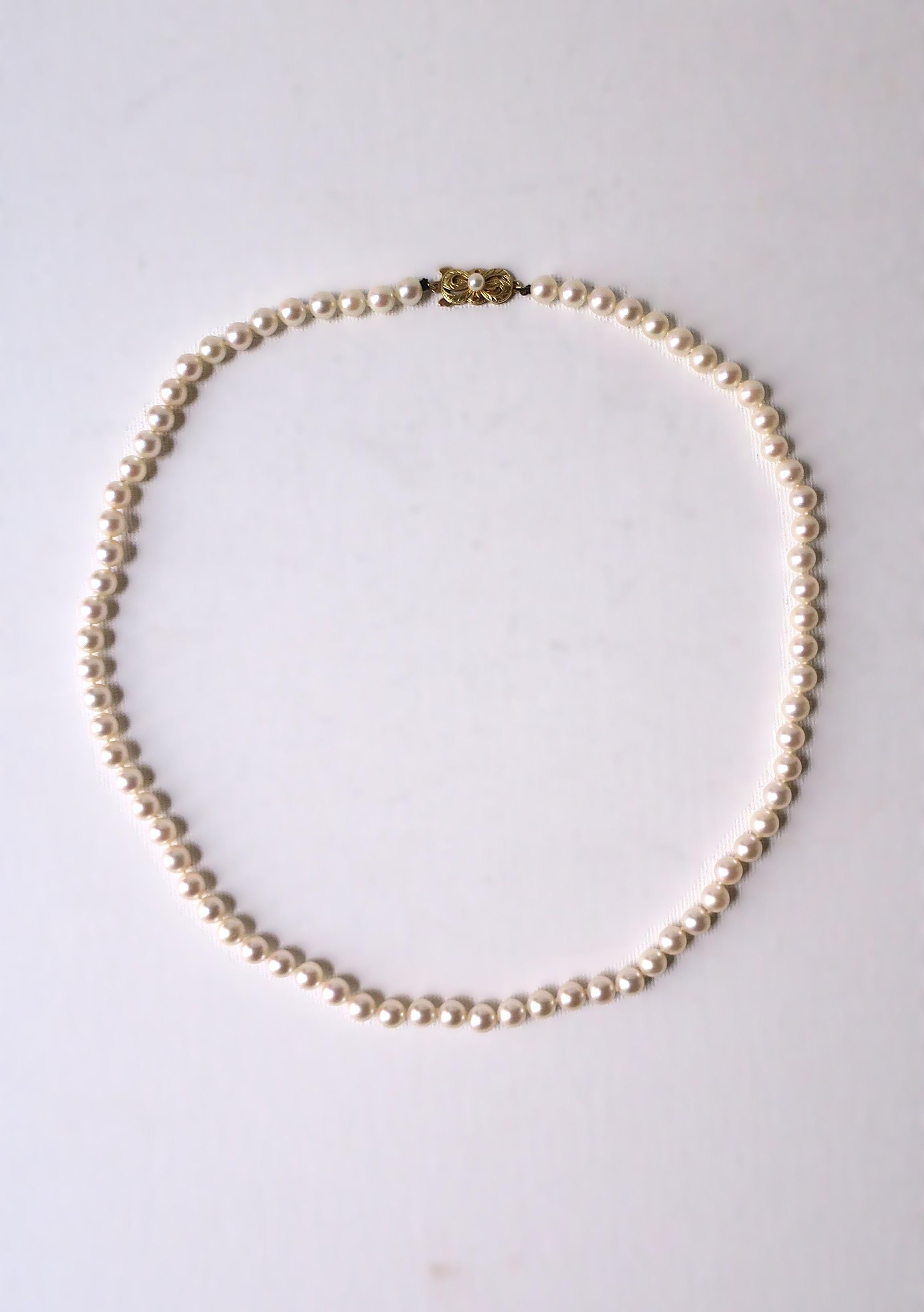 A beautiful Japanese saltwater cultured Akoya pearl necklace with 18-karat yellow gold clasp from luxury jewelry Maison, Mikimoto, circa 21st century, Japan. This stand, with beautiful luster and roundness, is strung and knotted on silk string, and