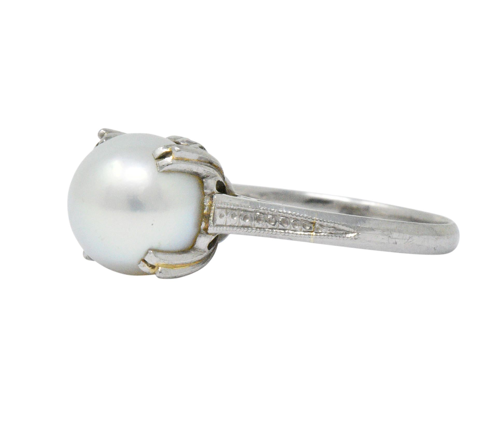 Centering a round cultured pearl, measuring approximately 9.0 mm

White body color with a rose overtone, very good luster and surface quality

Prong set in engraved platinum

Tested as platinum with early Mikimoto maker's mark

Ring Size: 7 &