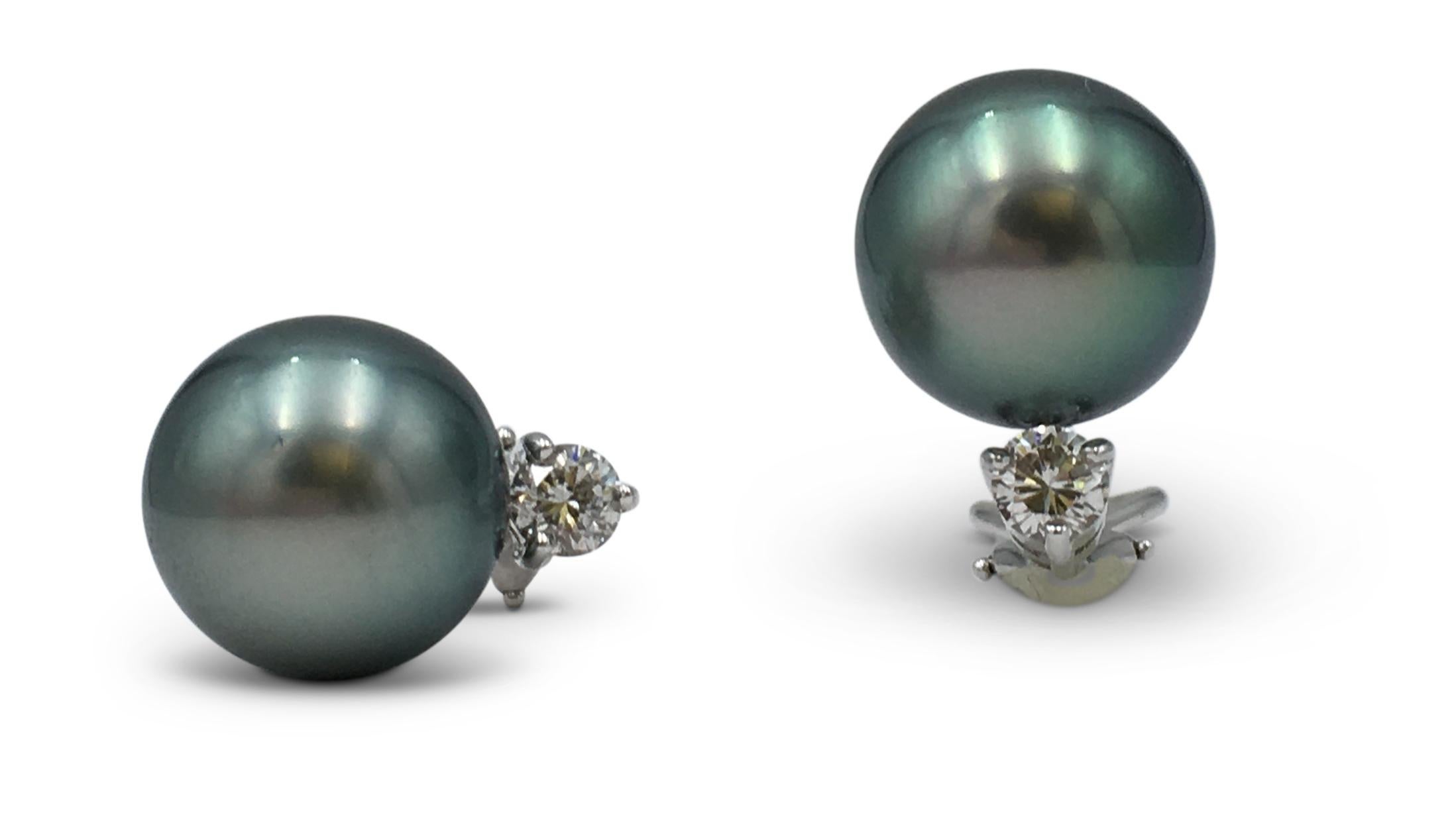 Authentic Mikimoto stud earrings crafted in 18 karat white gold.  Each earring features a stunning 8mm black south sea cultured 'Tahitian' pearl and a round brilliant cut diamond weighing approximately .20ct. Stamped M, 18K, 1338.  CIRCA
