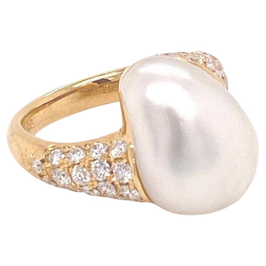 This lovely authentic ring is from Mikimoto, it is crafted from 18k yellow gold featuring an odd shape lustrous Akoya pearl mounted on a slim frame with a bit of a twisted shape flowing down to the band decorated with 83 points round cut sparkling
