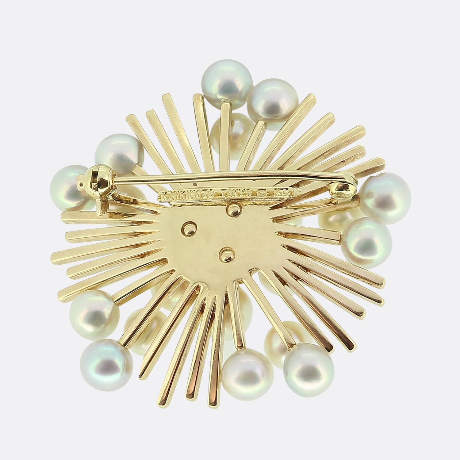 Hier haben wir eine unverwechselbare Brosche des Meisters der Perlen, Mikimoto. Das Stück zeigt ein dynamisches Design, bei dem runde weiße Perlen im Mittelpunkt stehen. Die Perlen sind in einem eleganten Muster angeordnet, das von der Mitte
