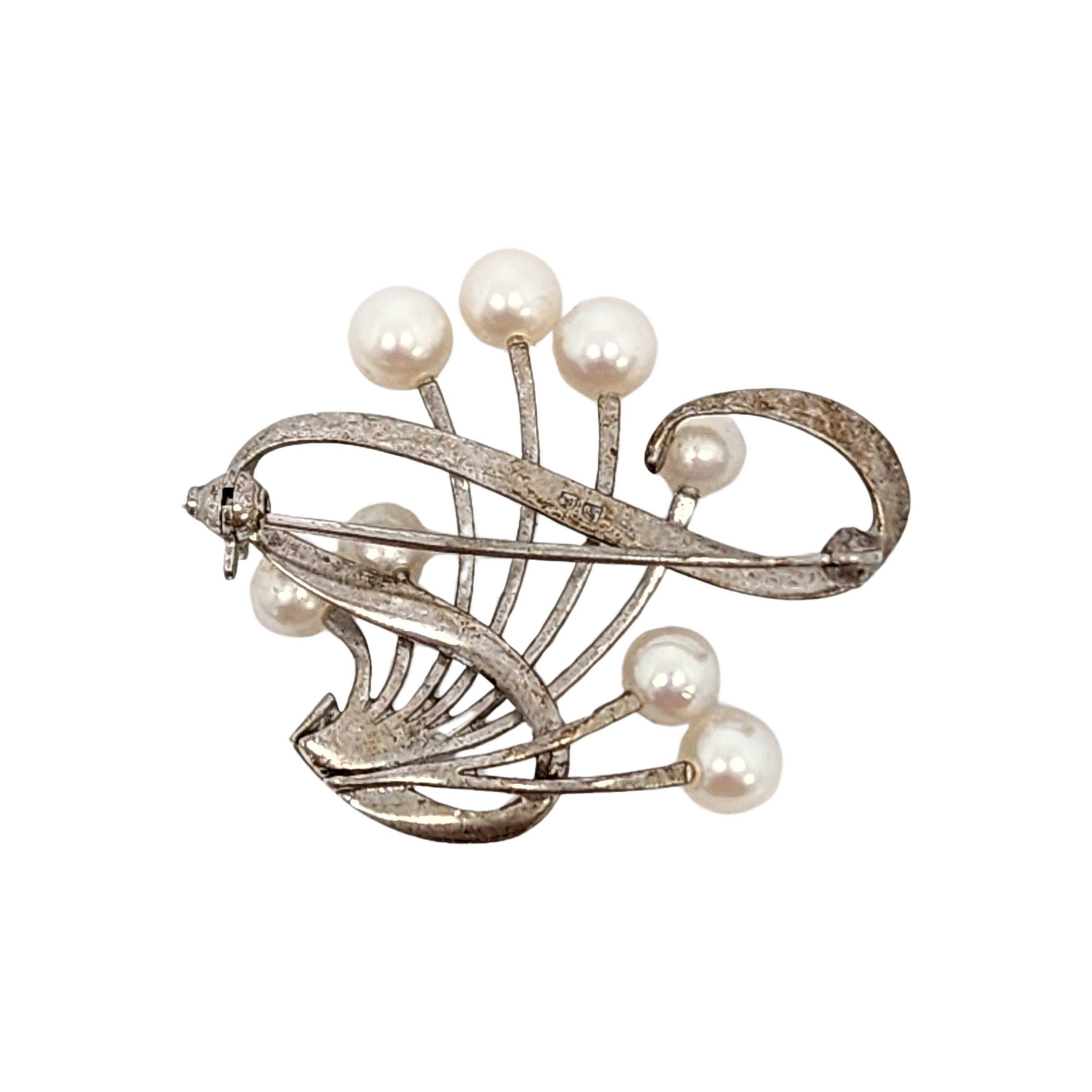 Akoya-Perlenbrosche aus Sterlingsilber von Mikimoto.

Wunderschönes Design mit 8 Perlen und einem verschnörkelten Band als Akzent. Kugelschließe und Scharnier.

Maße: ca. 1 1/8
