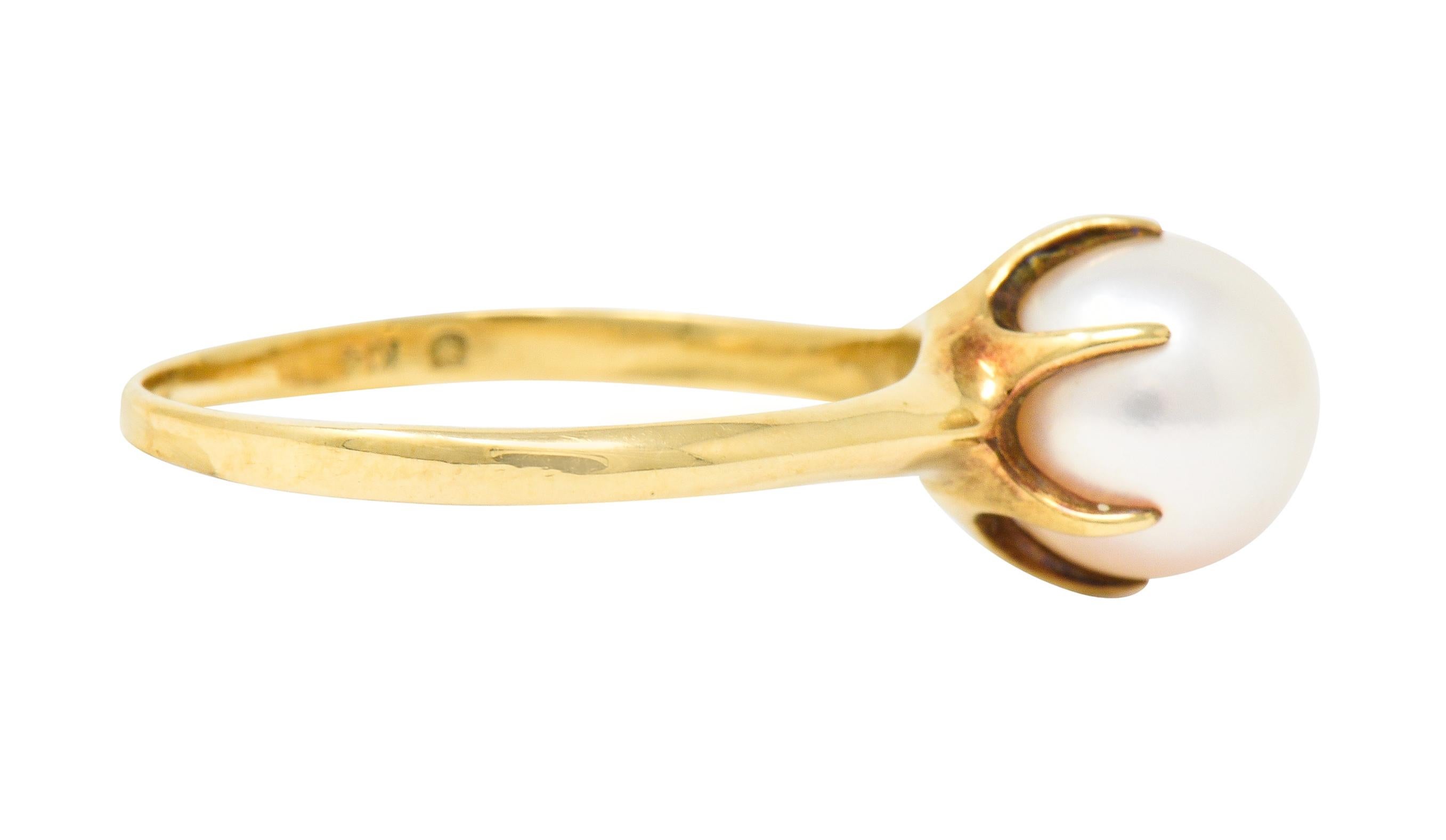 Centering a round cultured pearl measuring approximately 8.5 mm

Cream in body color with strong rosè overtone and excellent luster

Set in a polished gold pearl cup with striking talon prongs

Completed by a simple polished gold band with very