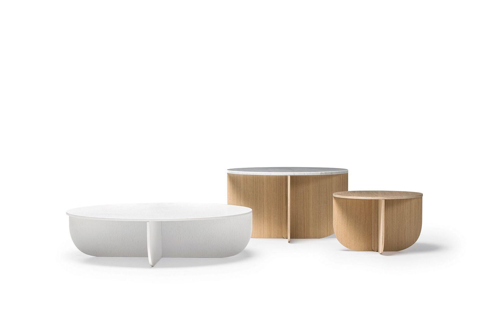 Une combinaison de quatre éléments de base, de trois matériaux raffinés et de deux couleurs sophistiquées. Le concept solide qui sous-tend cette table basse souligne les formes sobres et les qualités inhérentes au bois, au verre et au marbre. Des