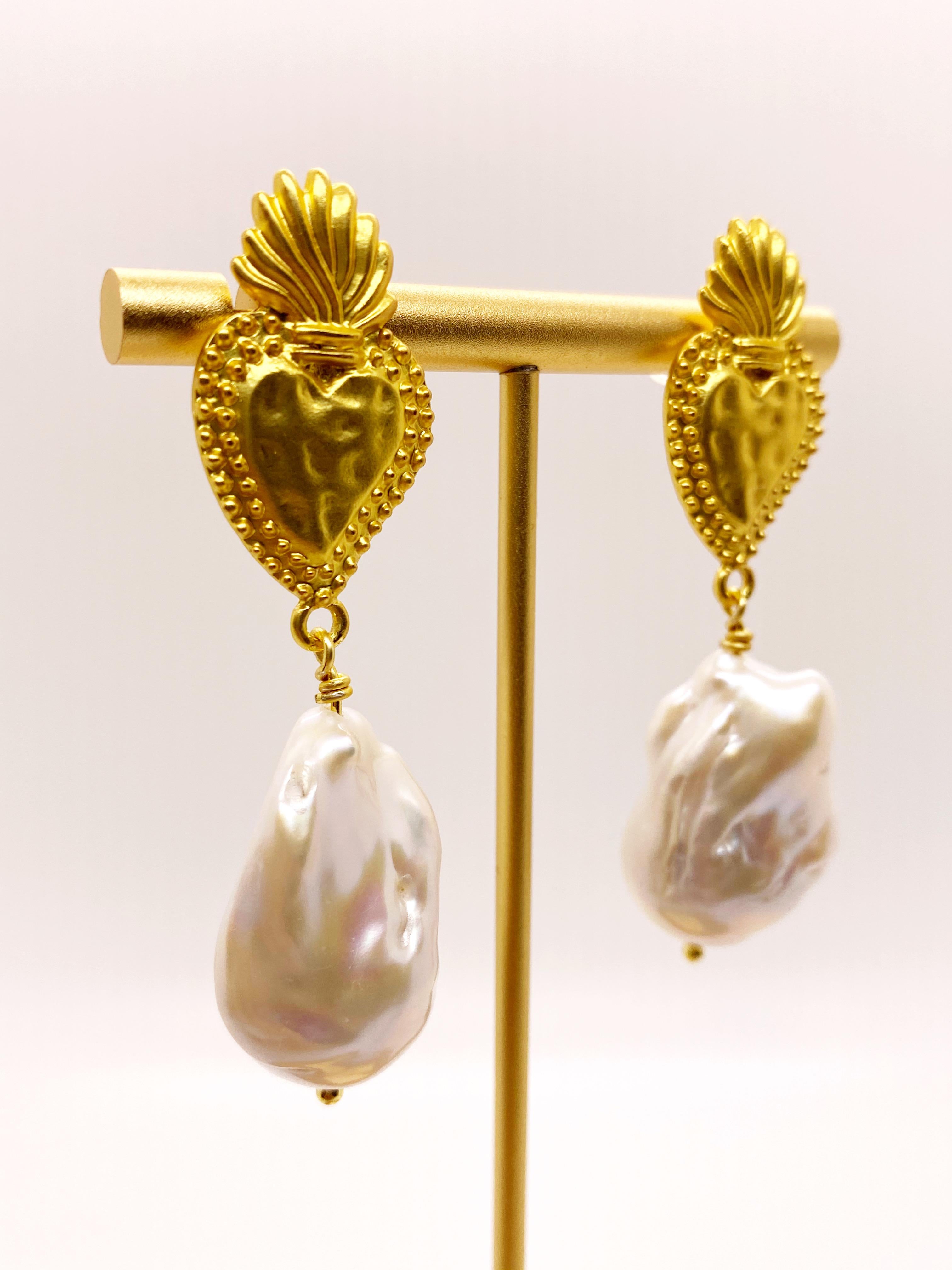 Une grande perle d'eau douce baroque blanche en forme de boule de flamme est suspendue à une tige de boucle d'oreille Milagrosa plaquée or. La taille et la forme des perles peuvent varier légèrement car il s'agit de perles naturelles. Boucles