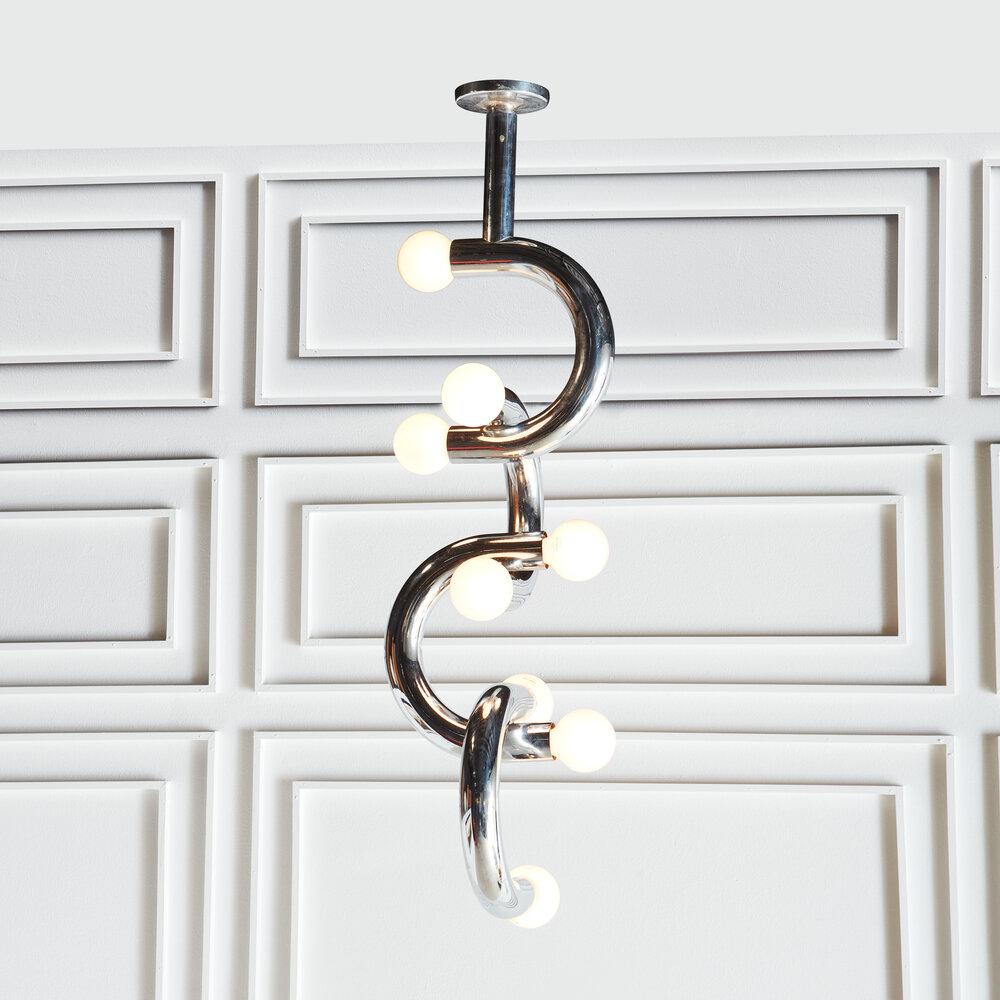 A sculptural chrome Stilux pendant light, composed of four interlocking C-shaped chrome tubes. Stilux was an Italian design company based in Milan during the 1970s, still well known for its modern designs.