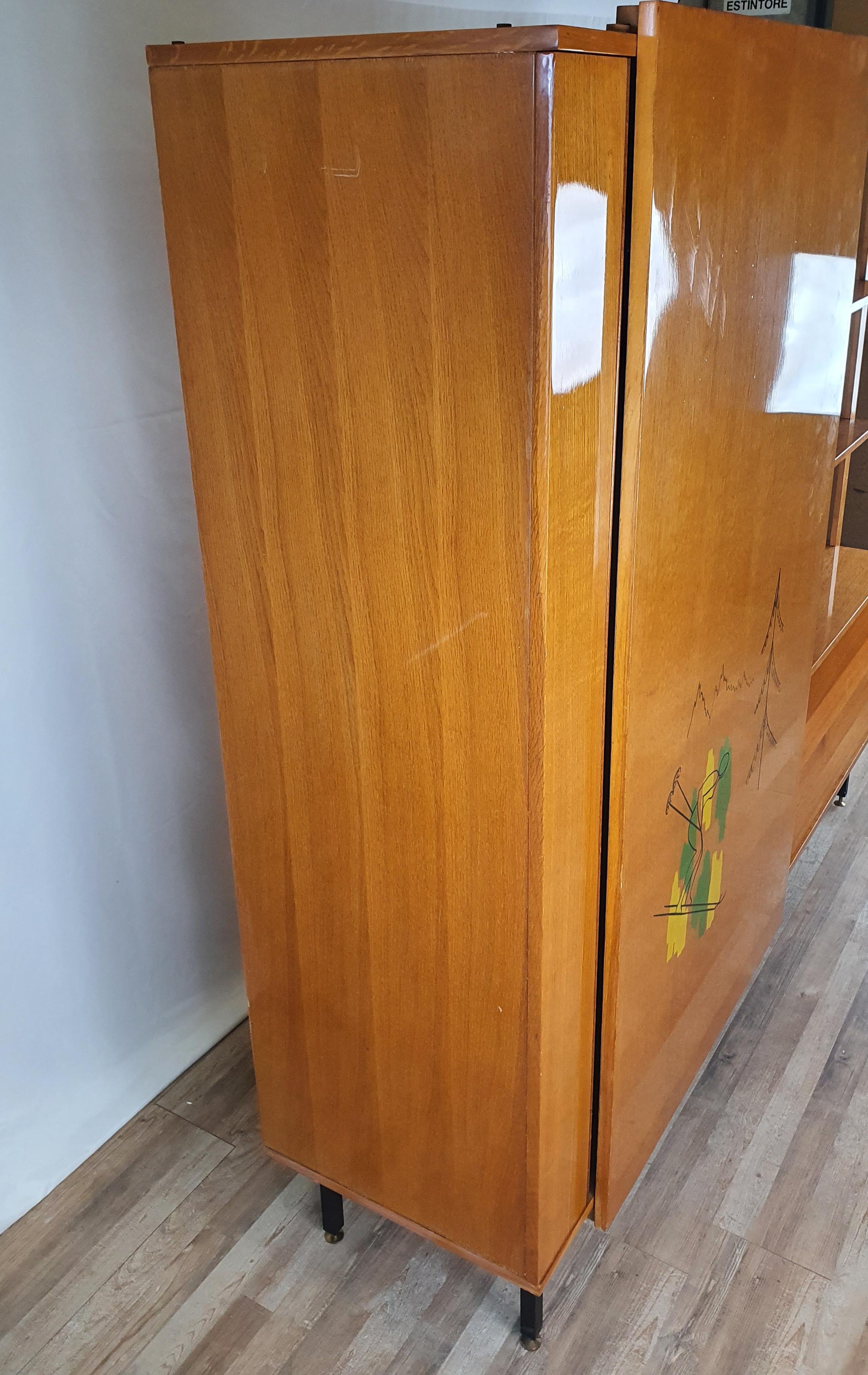 Elegant multipurpose furniture for living room or dining room in beech, Italian production from the early 1950s.

The sideboard has a decorated sliding door, covering an internal space with a shelf and double metal hanger.
On the right side we