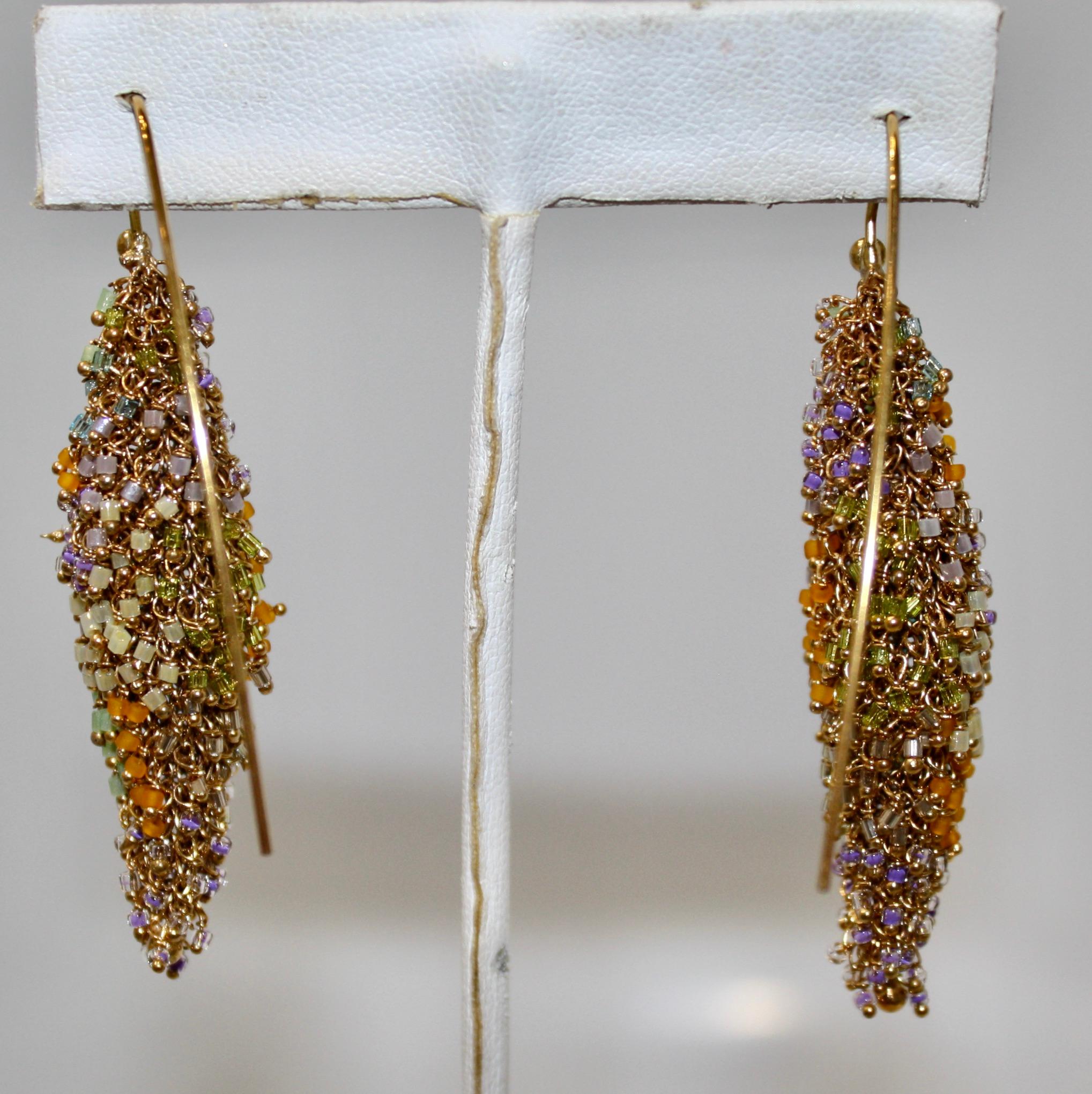 These edgy Milena Zu earrings are made of fine brass wire which is gold plated. It is decorated with hundreds of tiny Swarovski beads in shade of gold, green , orange and lavender. Each little bead is attached by hand and placed with