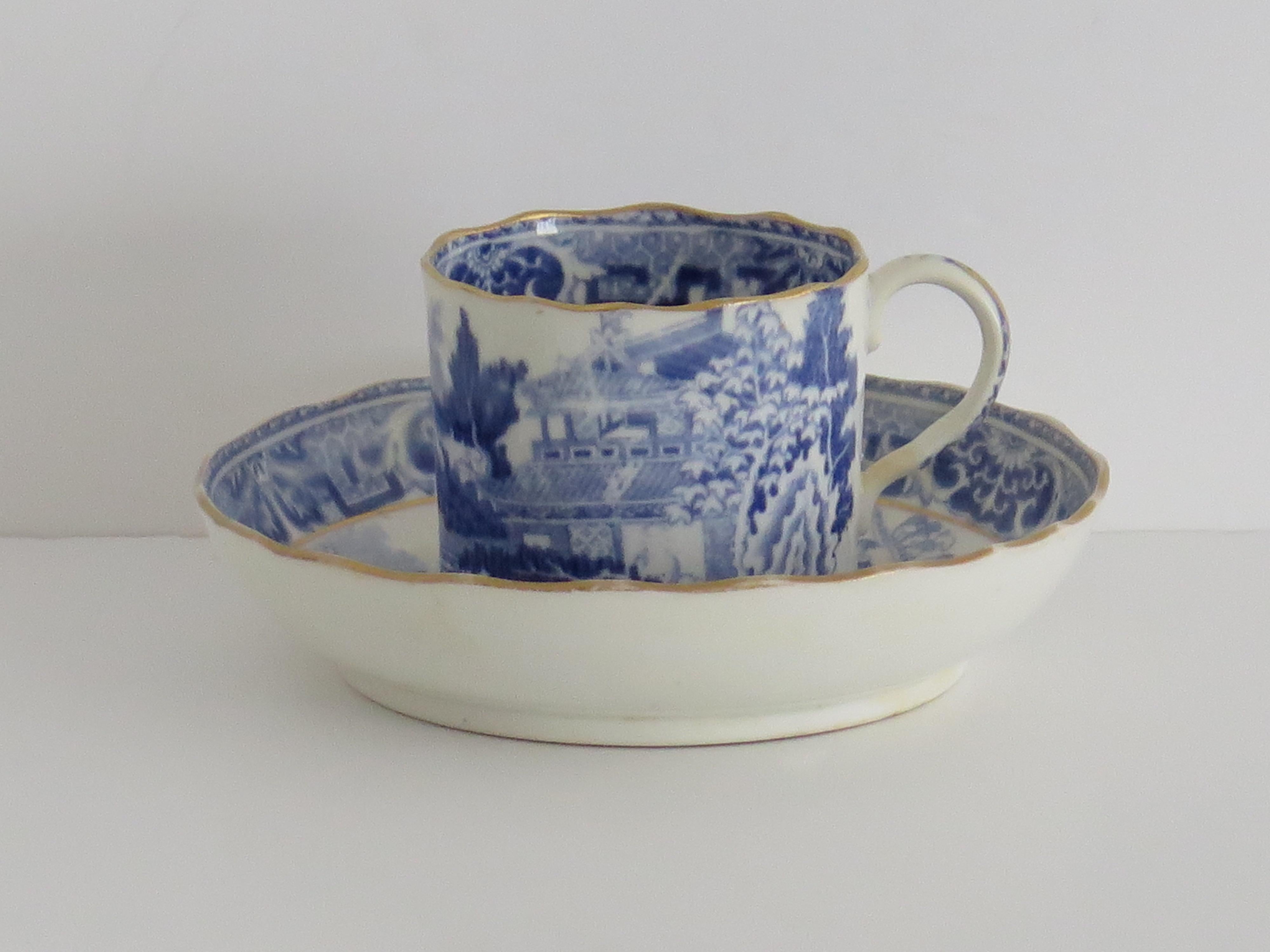This is a Miles Mason Duo of two pieces of blue and white hand gilded porcelain comprising a coffee can and a saucer, all in the Chinaman on Verandah pattern, made by Miles Mason (Mason's), Staffordshire Potteries, England around the turn of the