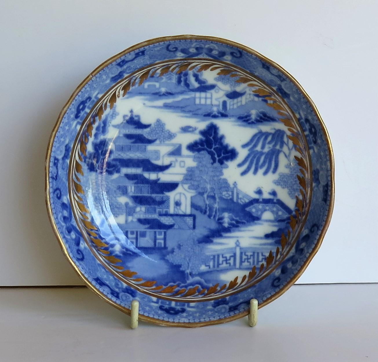 This is a Porcelain blue and white, hand gilded saucer dish made by Miles Mason (Mason's), Staffordshire Potteries, England around the turn of the 18th century, circa 1805. 

The dish is well potted on a low foot with slightly fluted sides and a