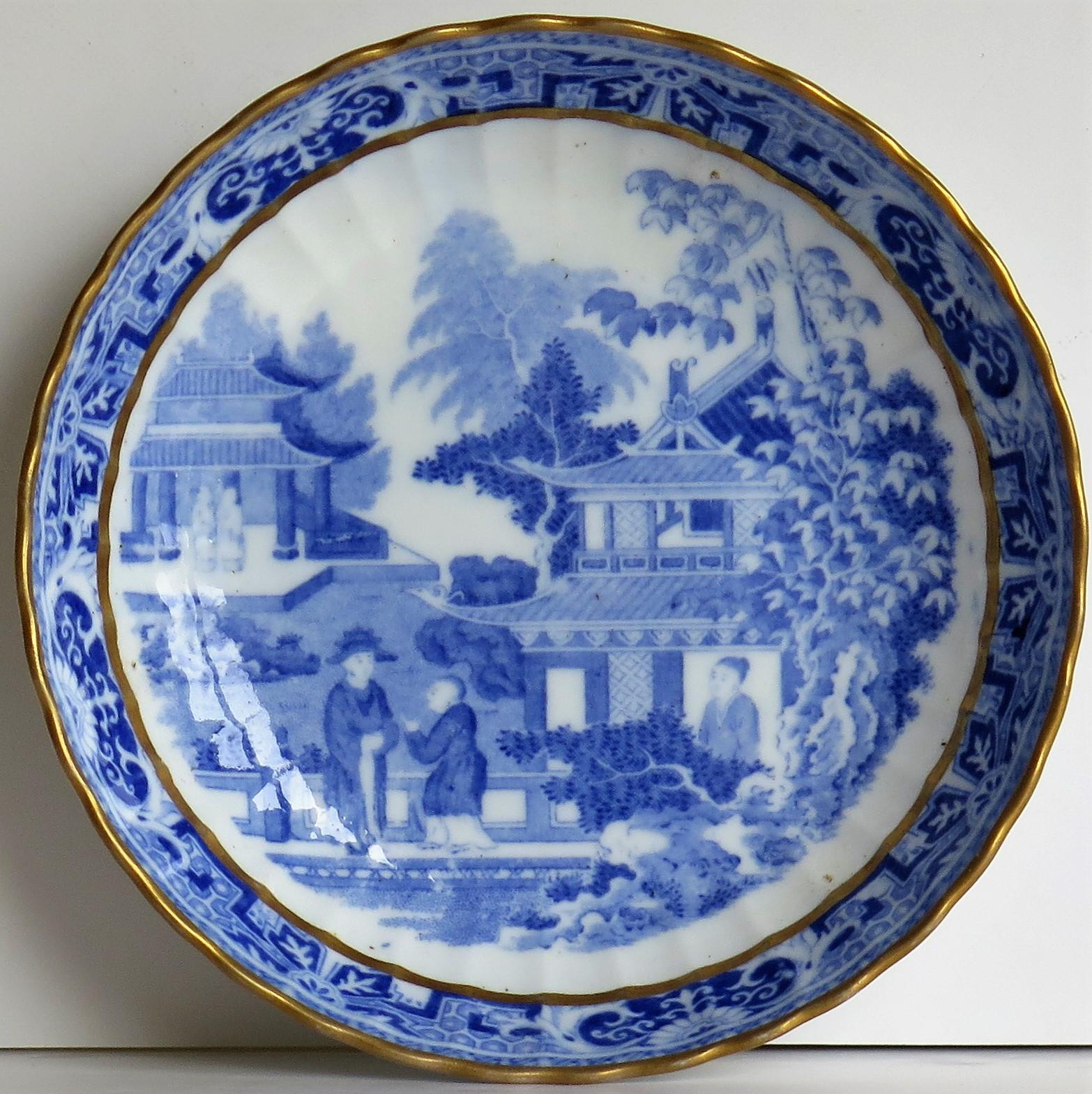 This is a porcelain blue and white, hand gilded Saucer Dish made by Miles Mason (Mason's), Staffordshire Potteries, England around the turn of the 18th century, circa 1805.

The dish is well potted on a low foot with fluted sides and a scalloped