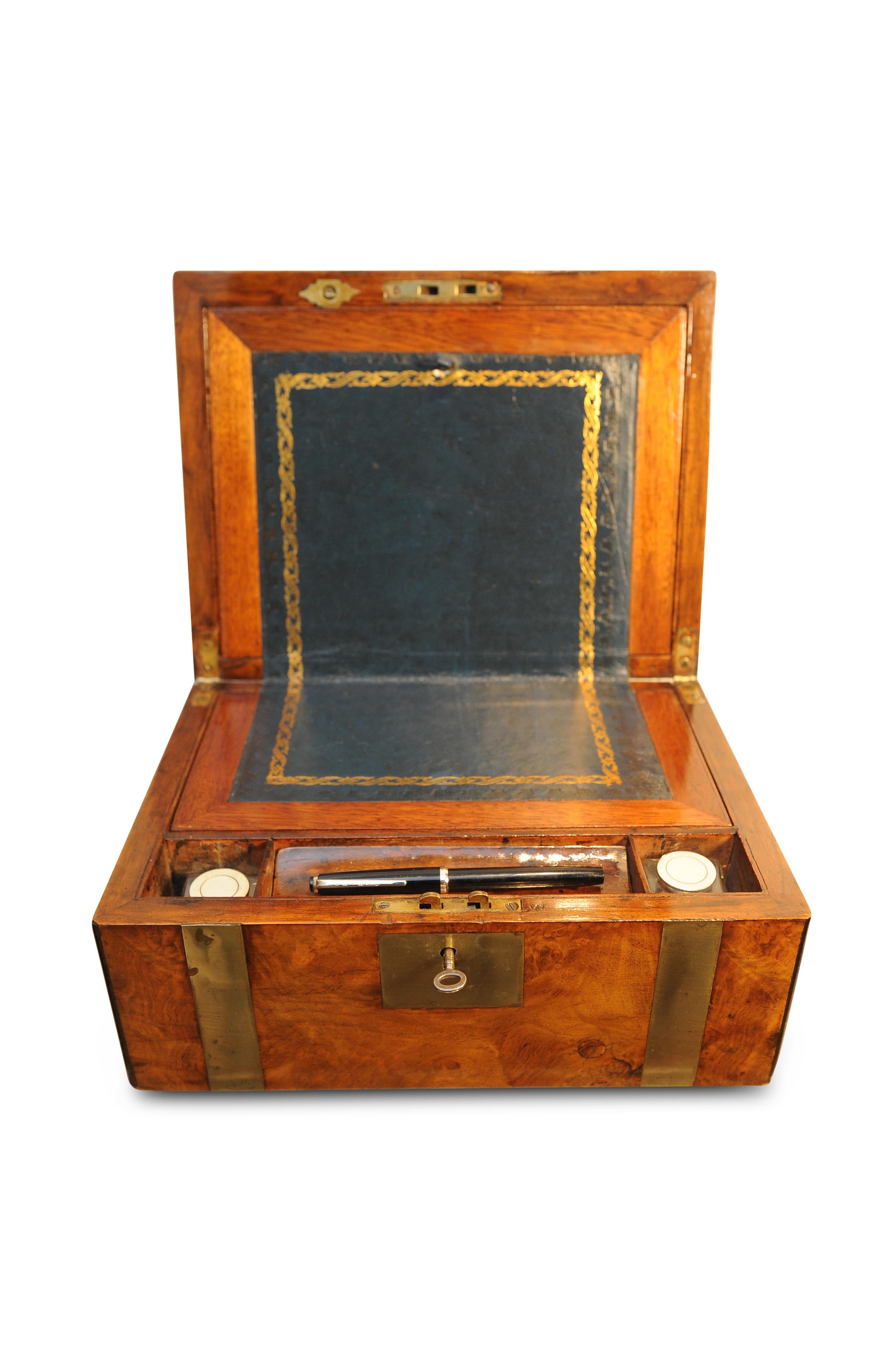 A Military Campaign brass bound walnut veneered writing slope with ebonised edging,
opening to reveal the usual fitted interior with tooled black leather skiver.
2 glass ink pots with silver plate lids in separate compartments.
1 key included for