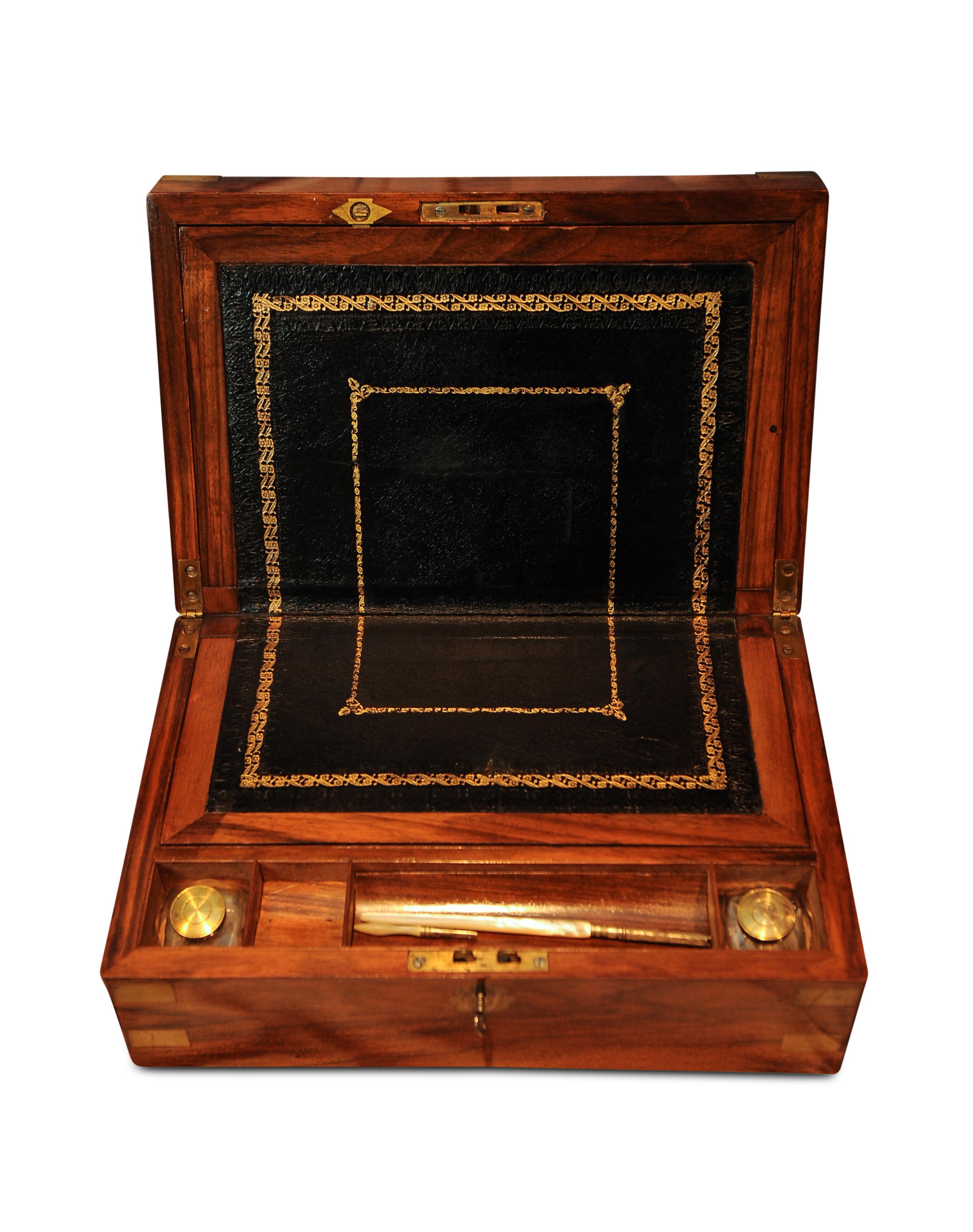 A military Campaign brass bound walnut veneered writing slope, with flower front motif. 
Opening up to reveal the usual fitted interior with embossed black leather top.
With two glass ink pots in separate compartments with brass lids.
Key